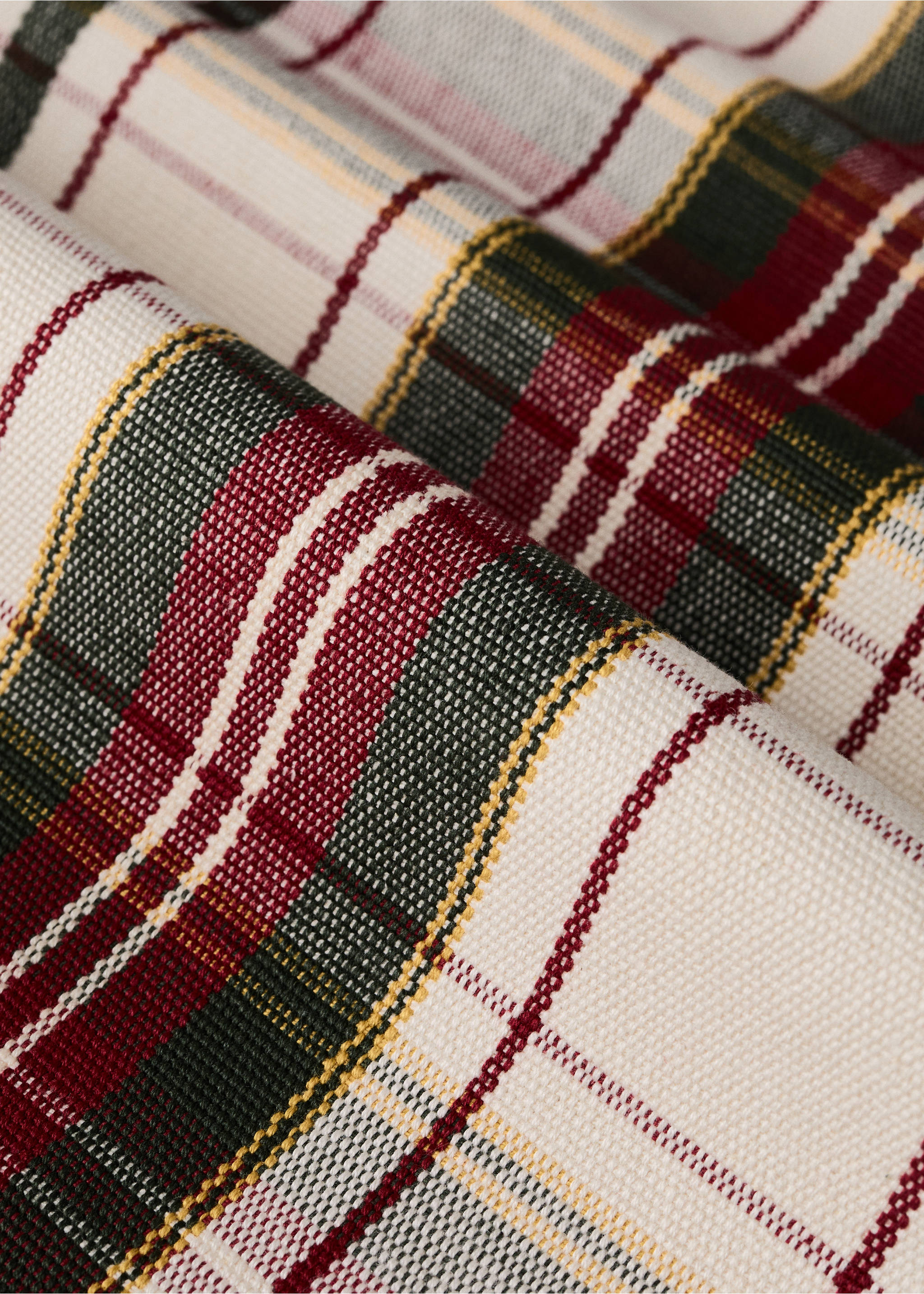 Close-up of a cream table runner with a red, dark green, and yellow tartan plaid pattern., Red. Ref: 37056733-00.