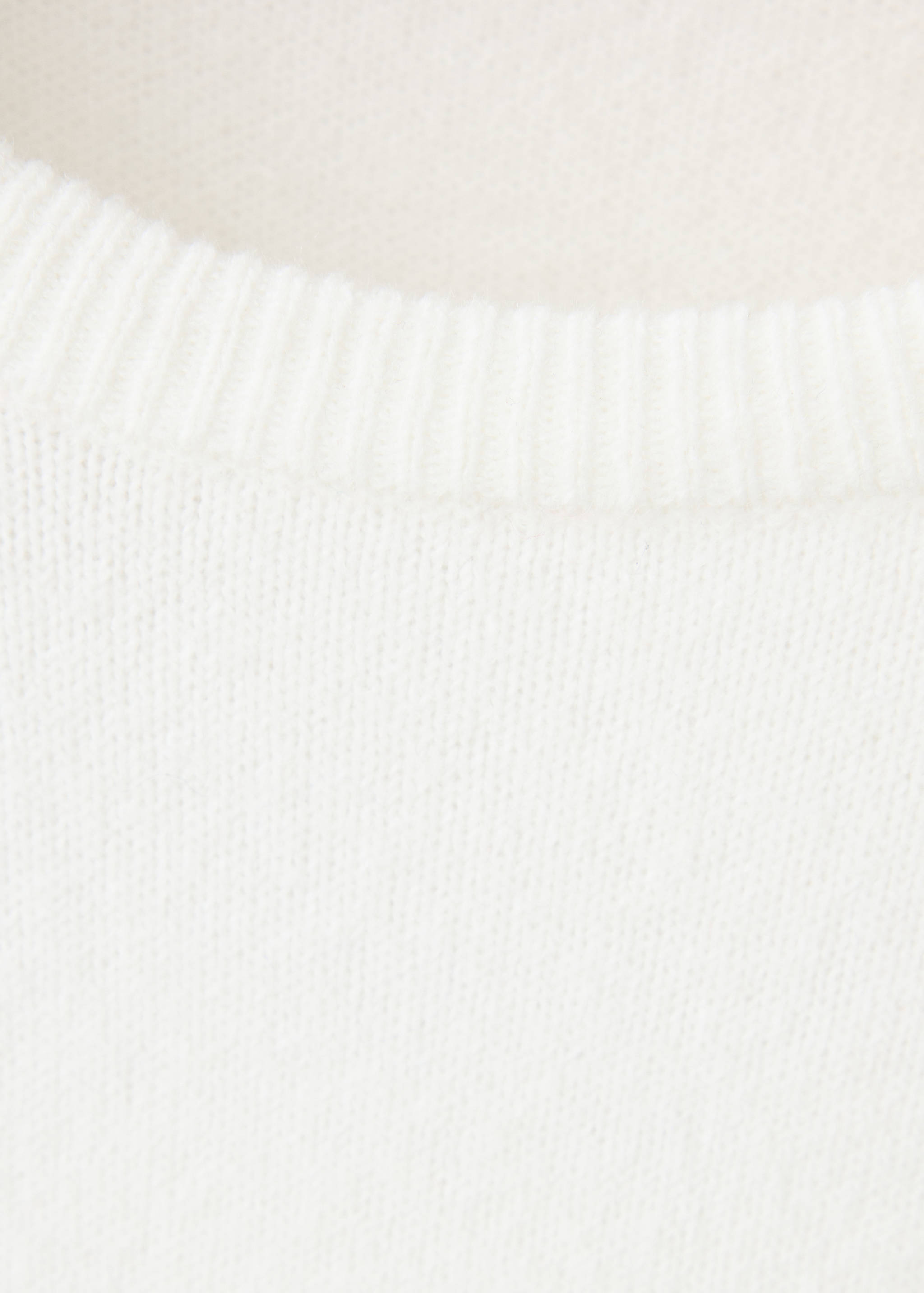 Close-up of the off-white jersey knit fabric and ribbed neckline.