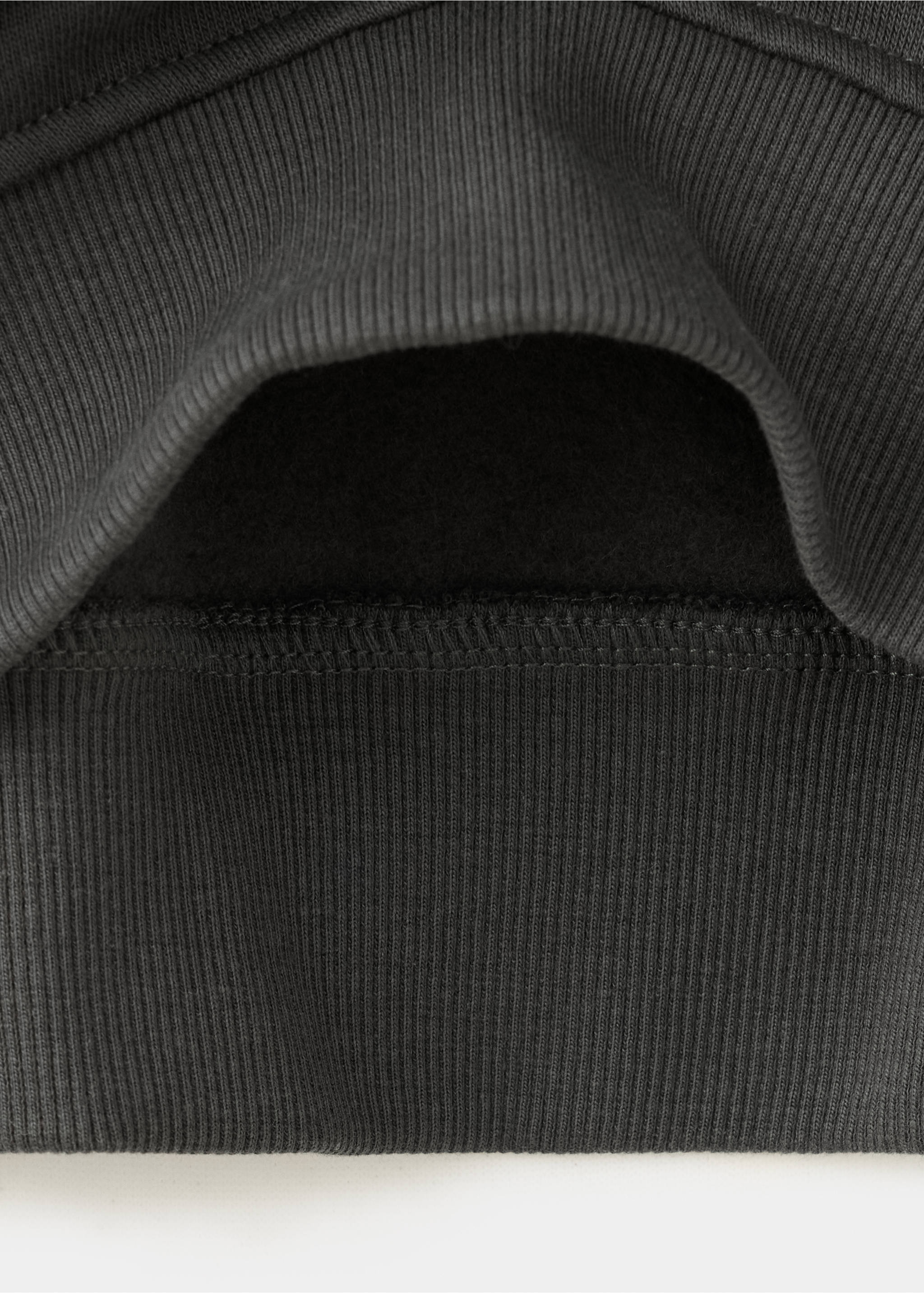 Primer plano de la textura del tejido y el dobladillo de canalé de una sudadera gris oscuro., Gris antracita. Ref: 37056742-00.