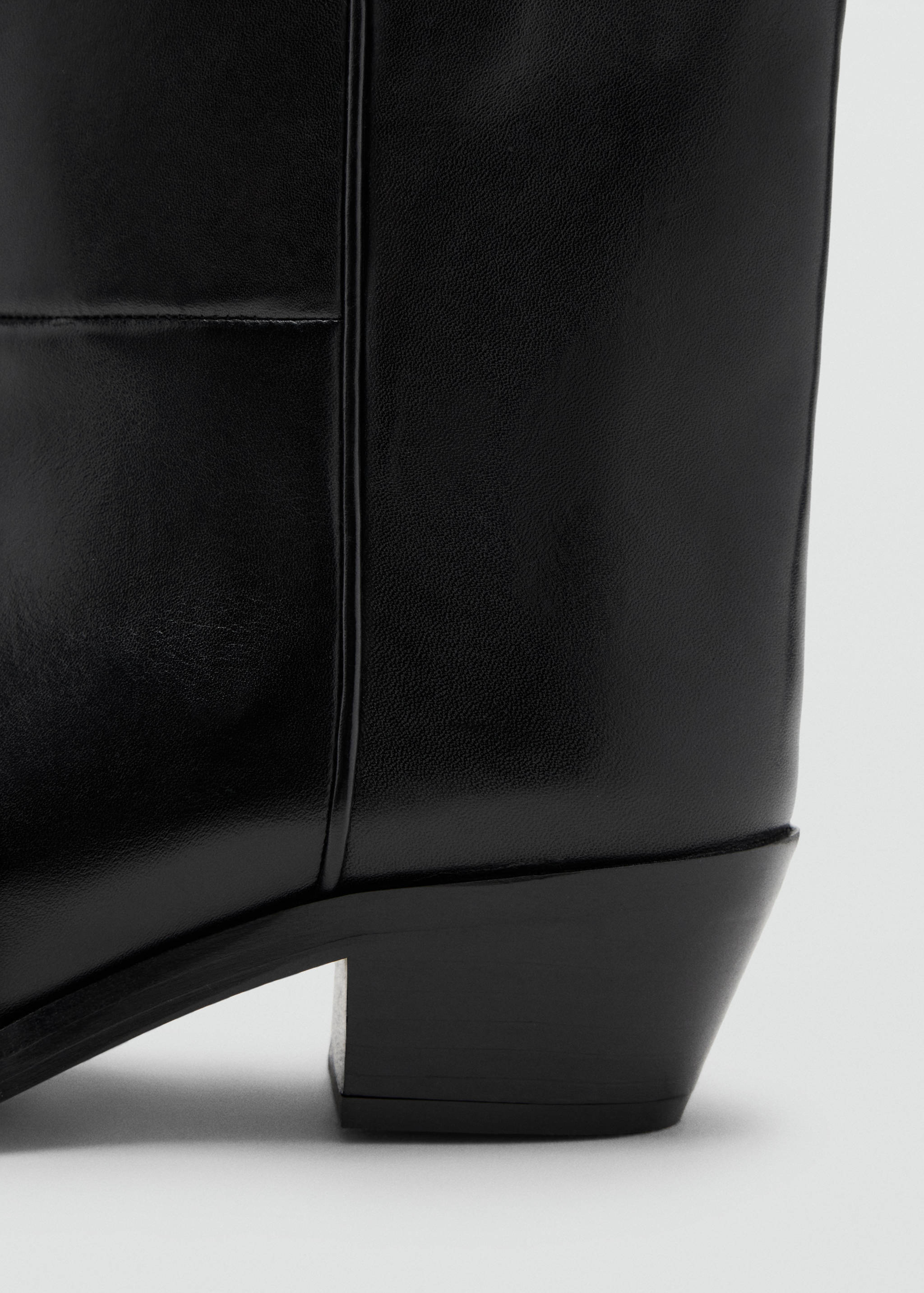 Close-up of black ankle boot showing the heel and side detail.