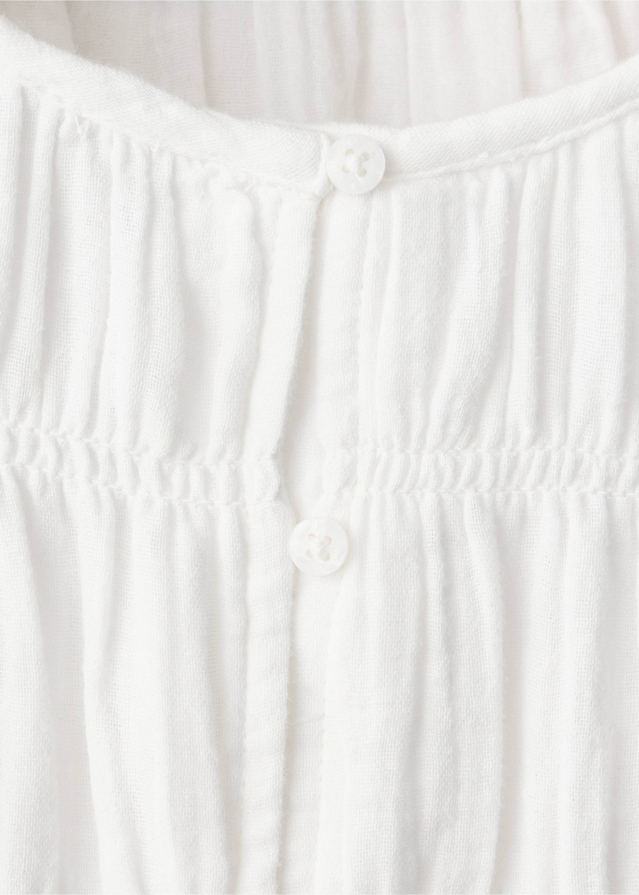 Close-up of a white kids' shirt featuring gathered texture and front buttons., White. Ref: 37057136-00.
