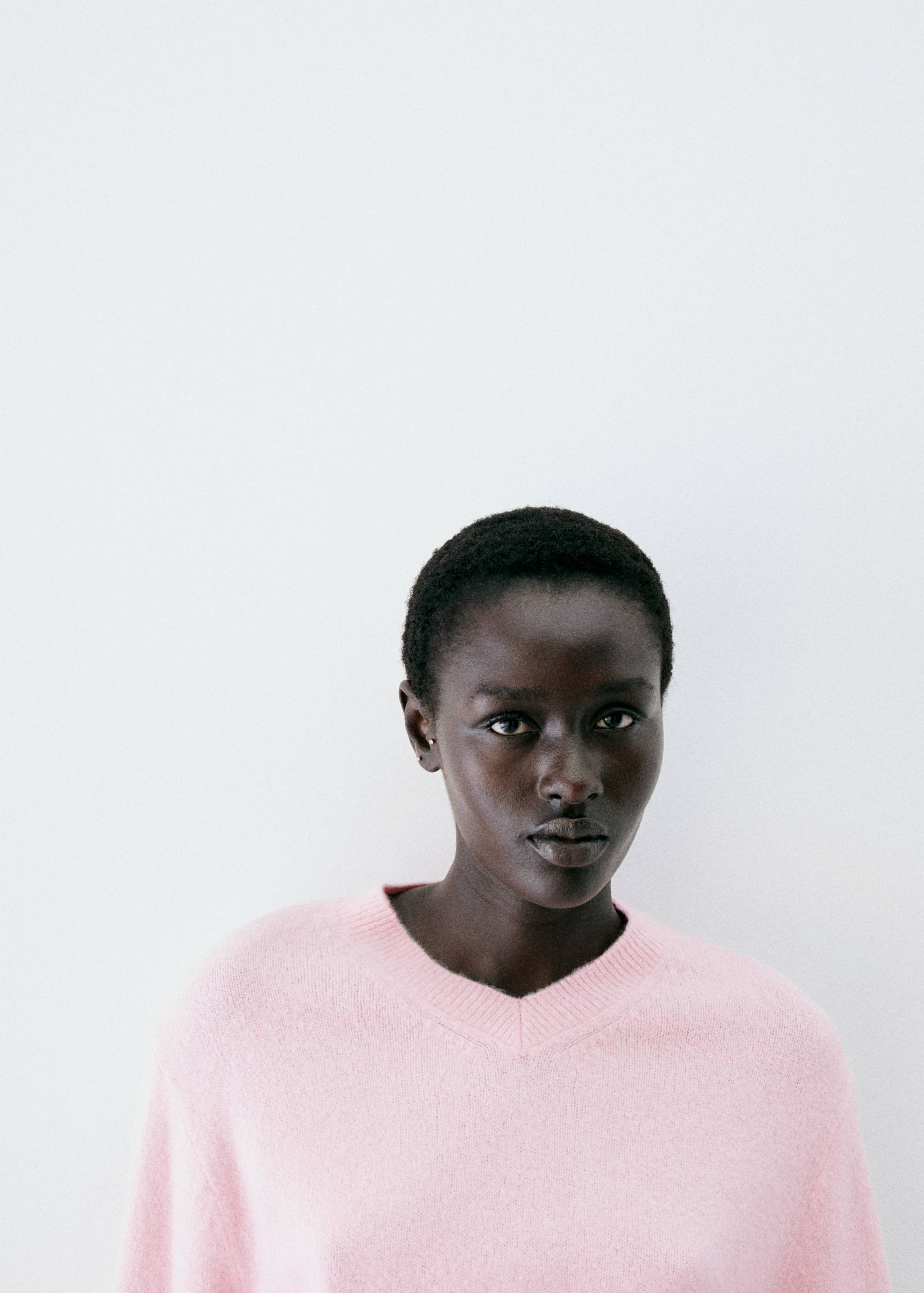 Pink knit jumper with a ribbed V-neckline.
