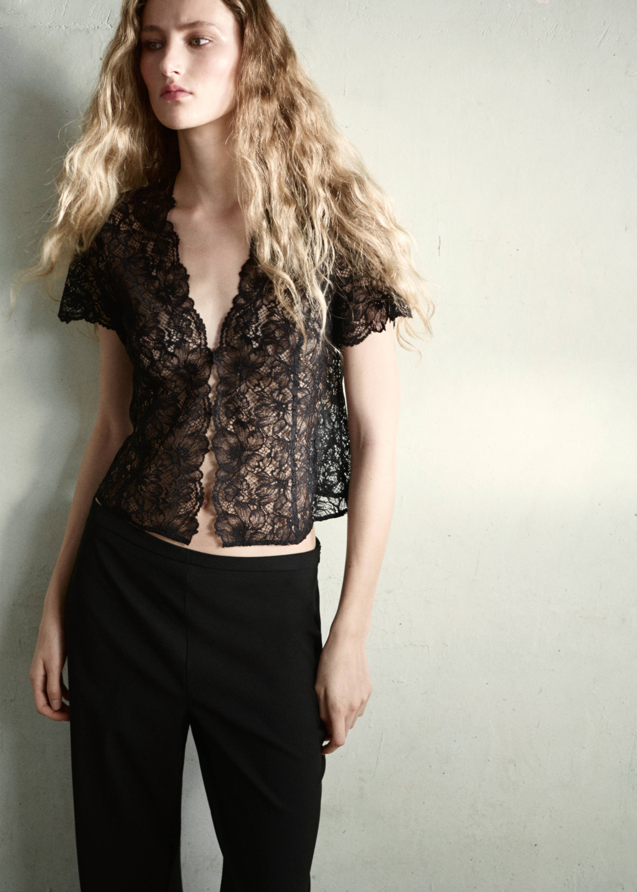 Plain black trousers worn with a black lace top.
