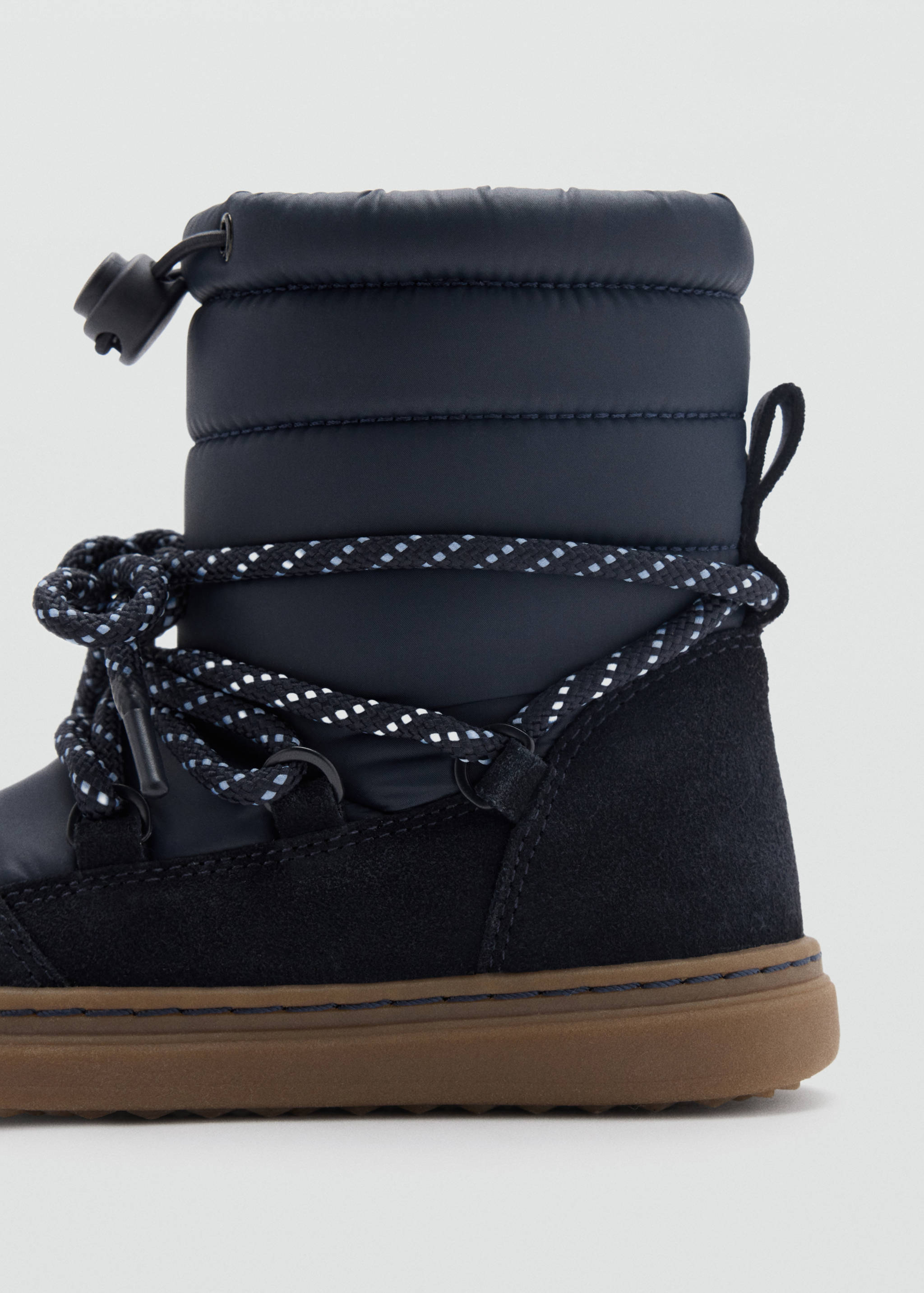 Close-up of a dark blue kids' boot with quilted shaft and patterned laces.