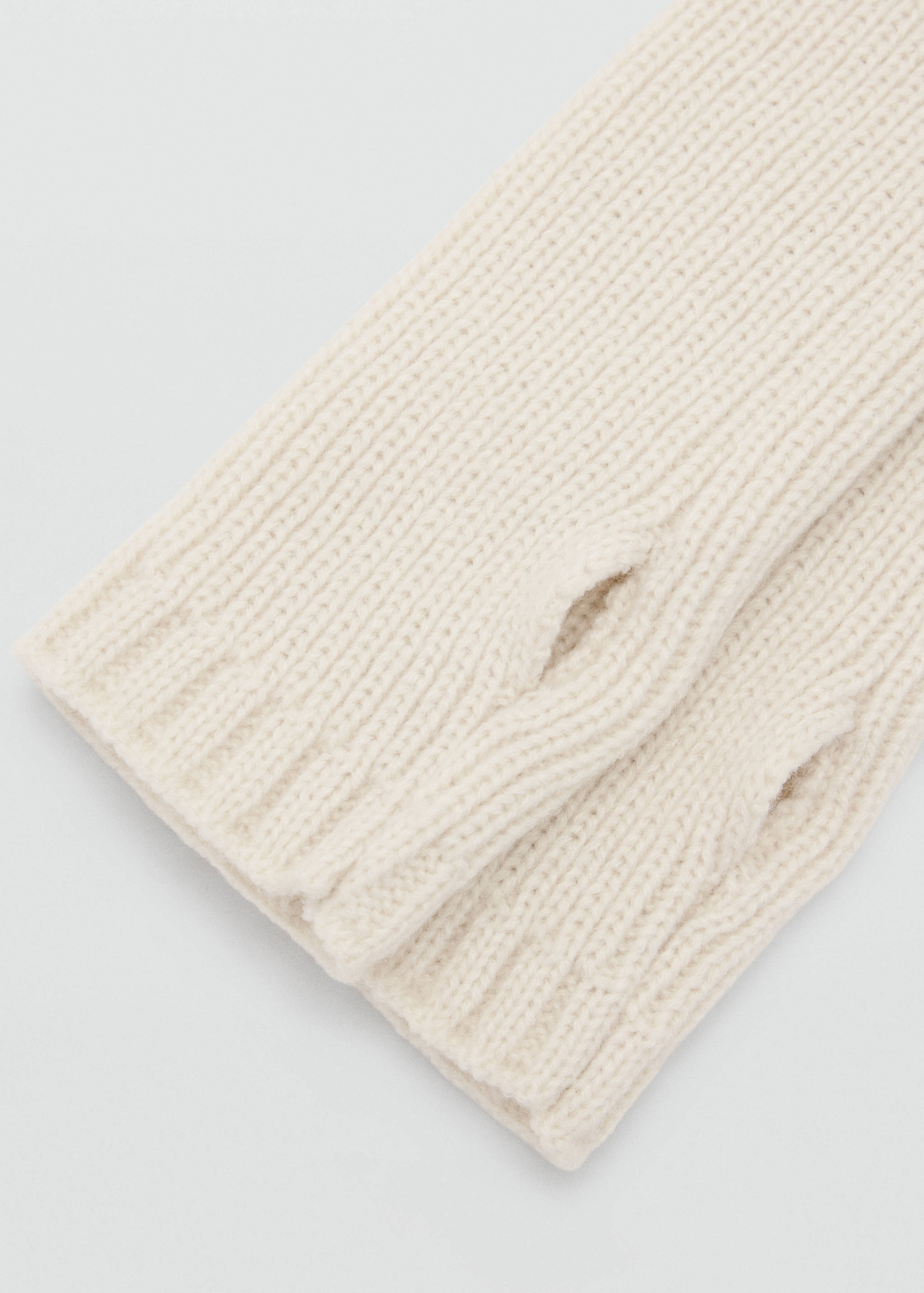 Close-up of off-white knitted gloves with ribbed texture and thumb openings.