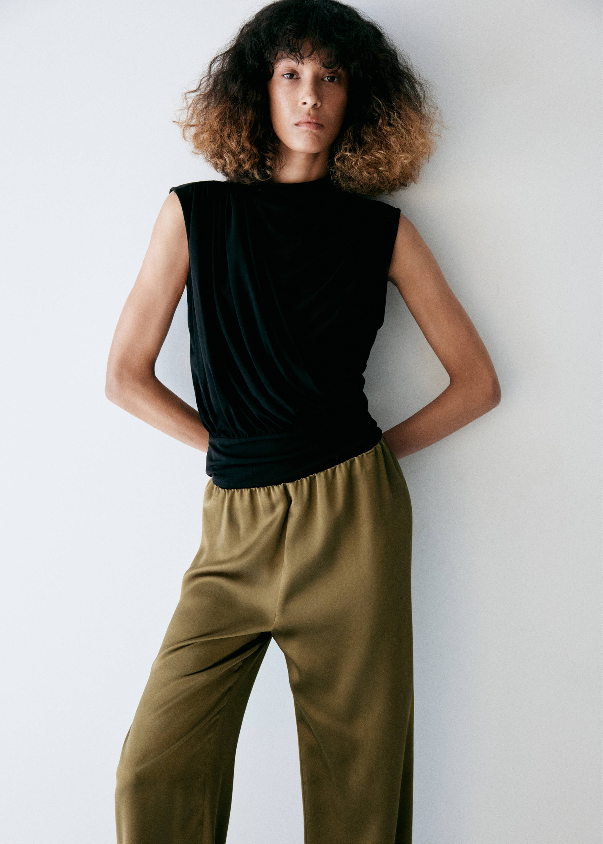 Olive green satin trousers with an elasticated waist, paired with a black sleeveless top.