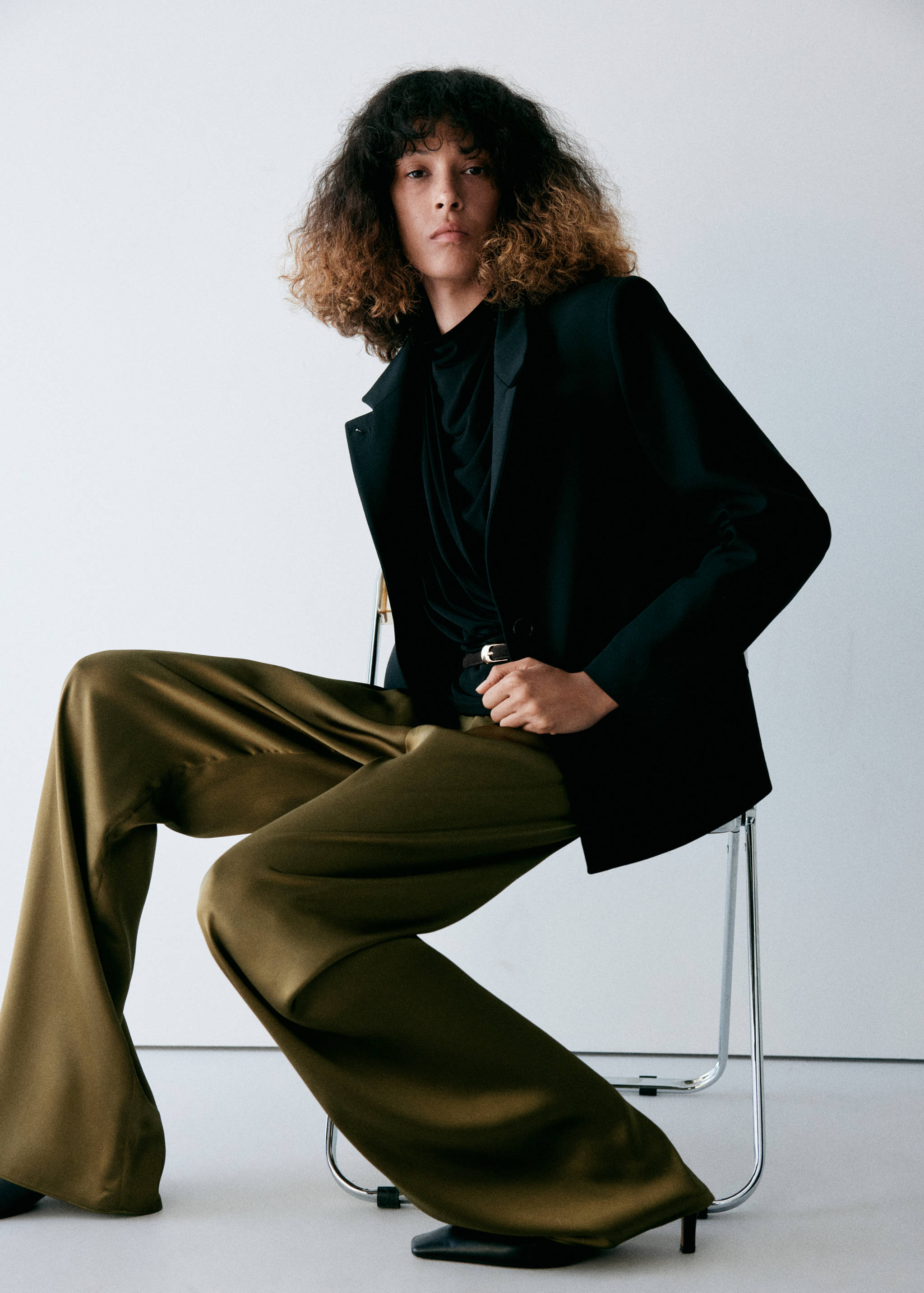 Olive green satin wide-leg trousers worn with a black blazer and top.