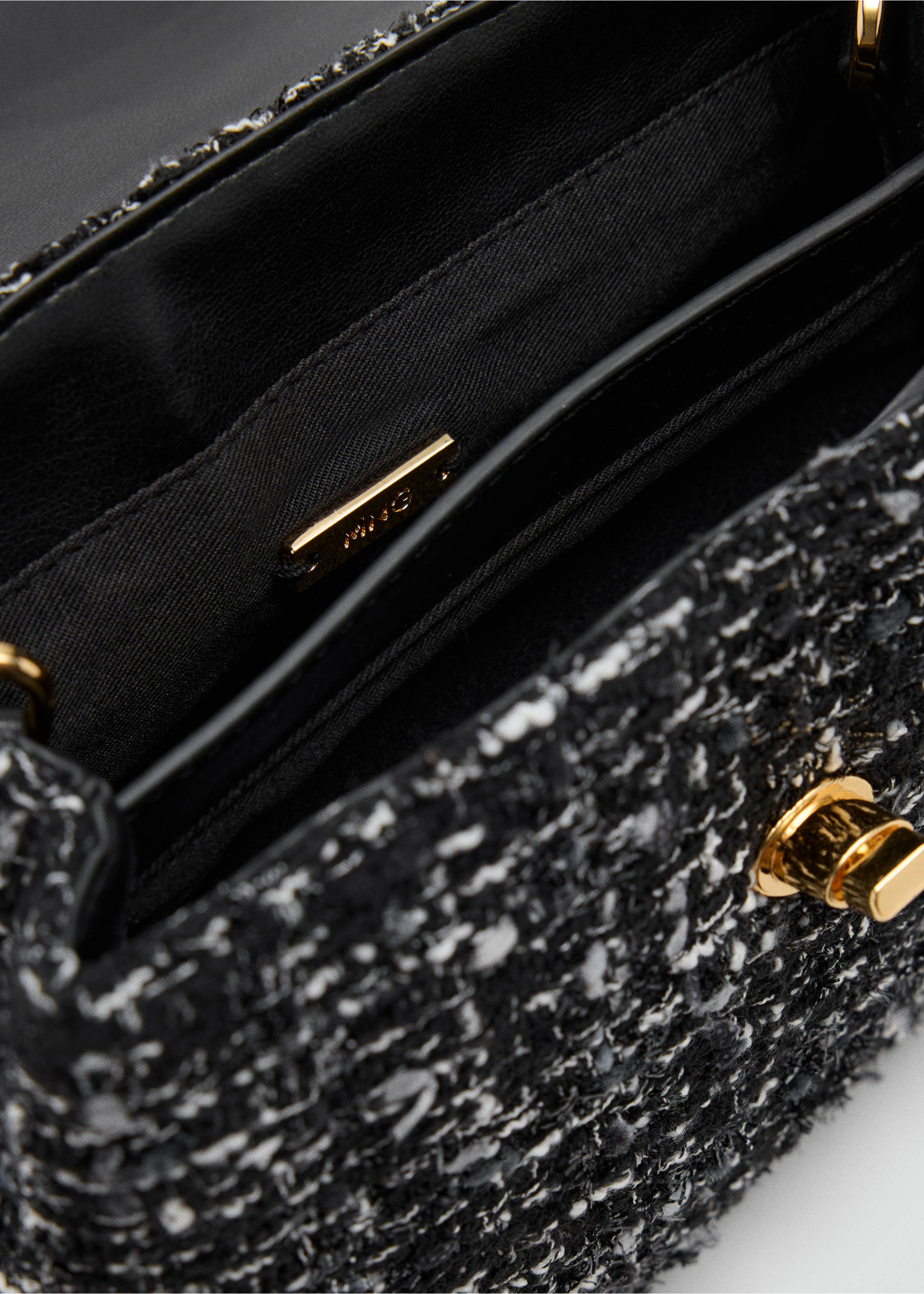 Detalle del interior de un bolso de mano de tweed en blanco y negro con detalles metálicos dorados., Negro. Ref: 37057807-00.