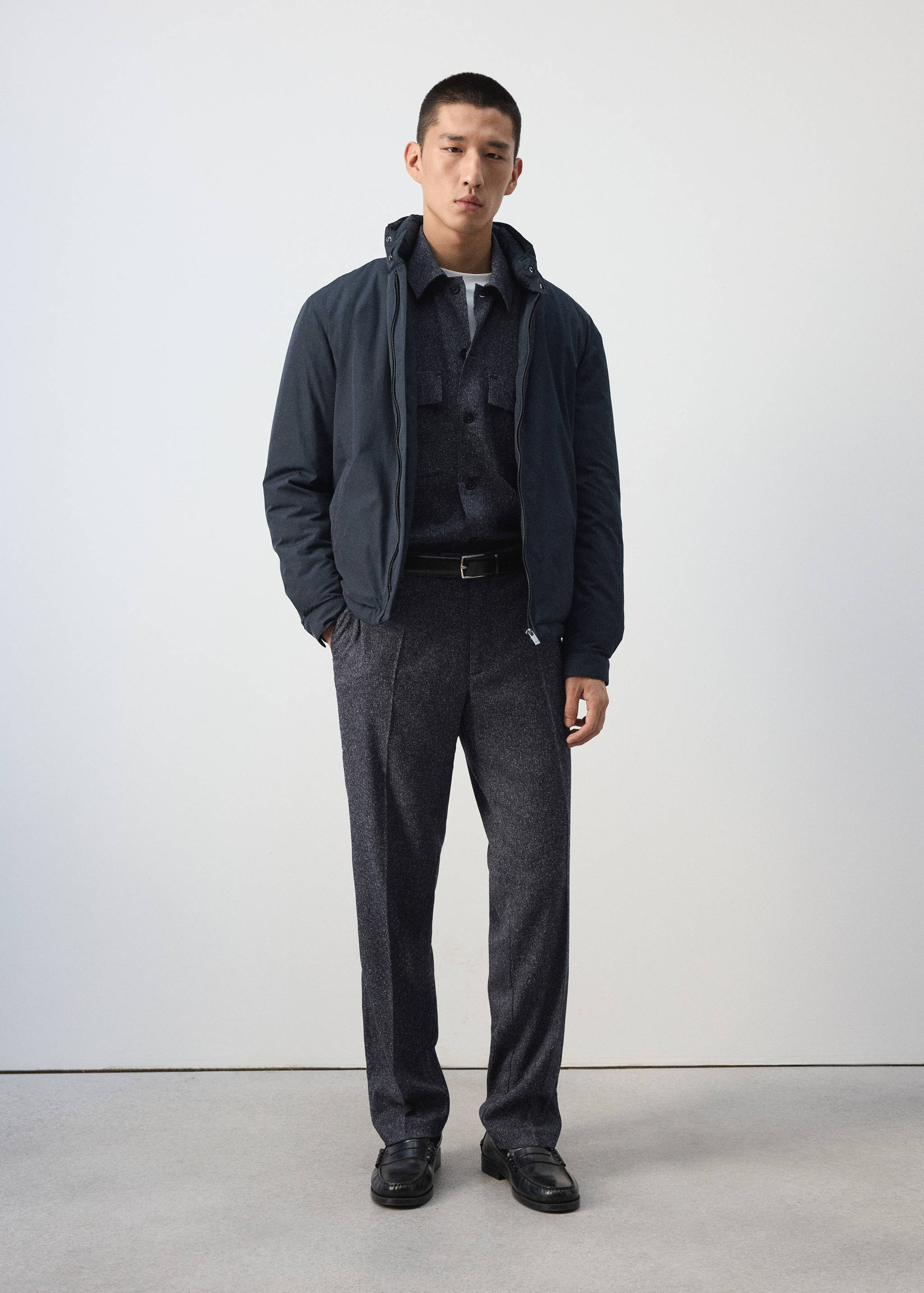 Navy blue zip-up jacket with a high collar, worn with matching dark trousers.