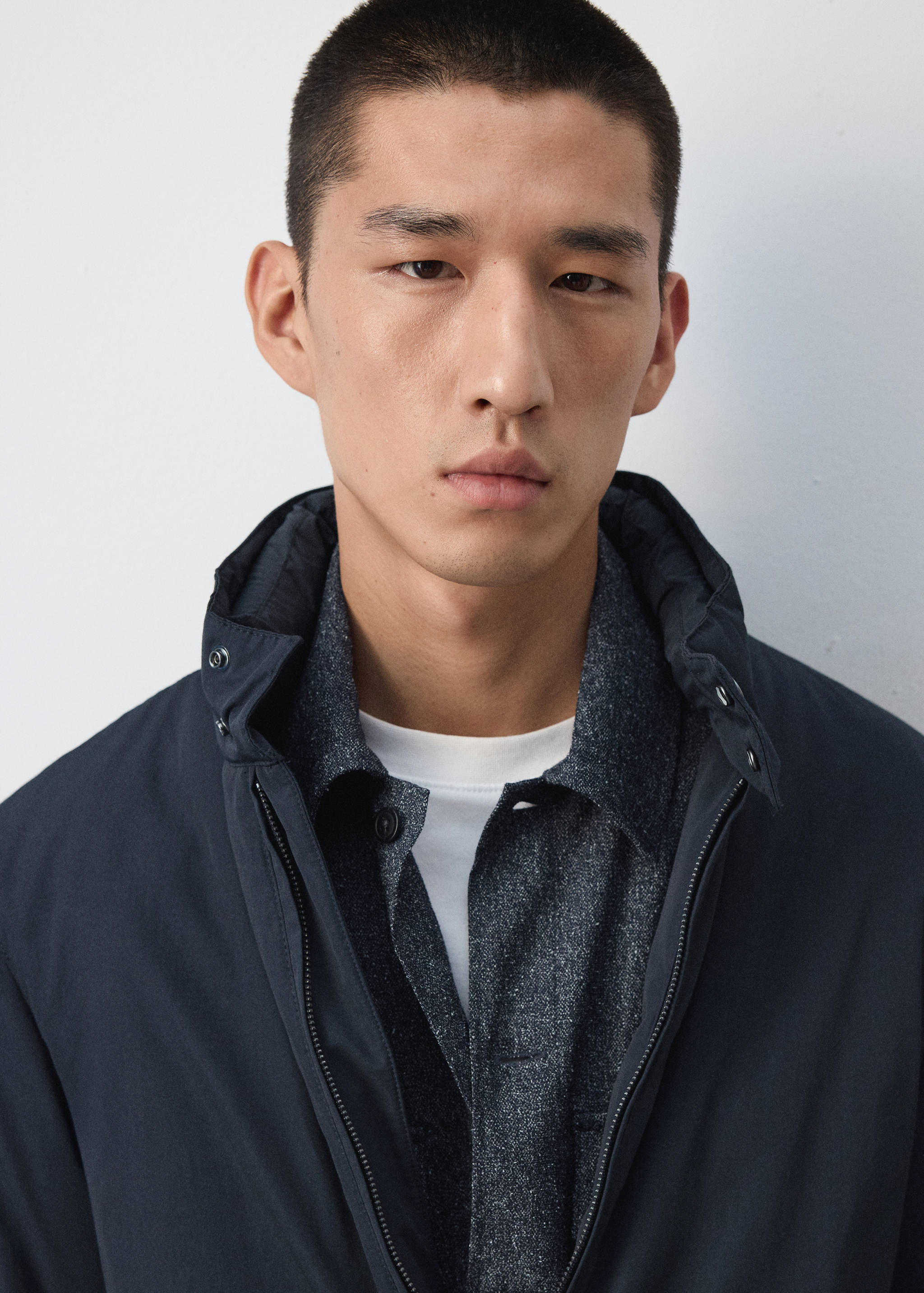 Close-up of a model wearing a dark navy blue jacket with a high collar.