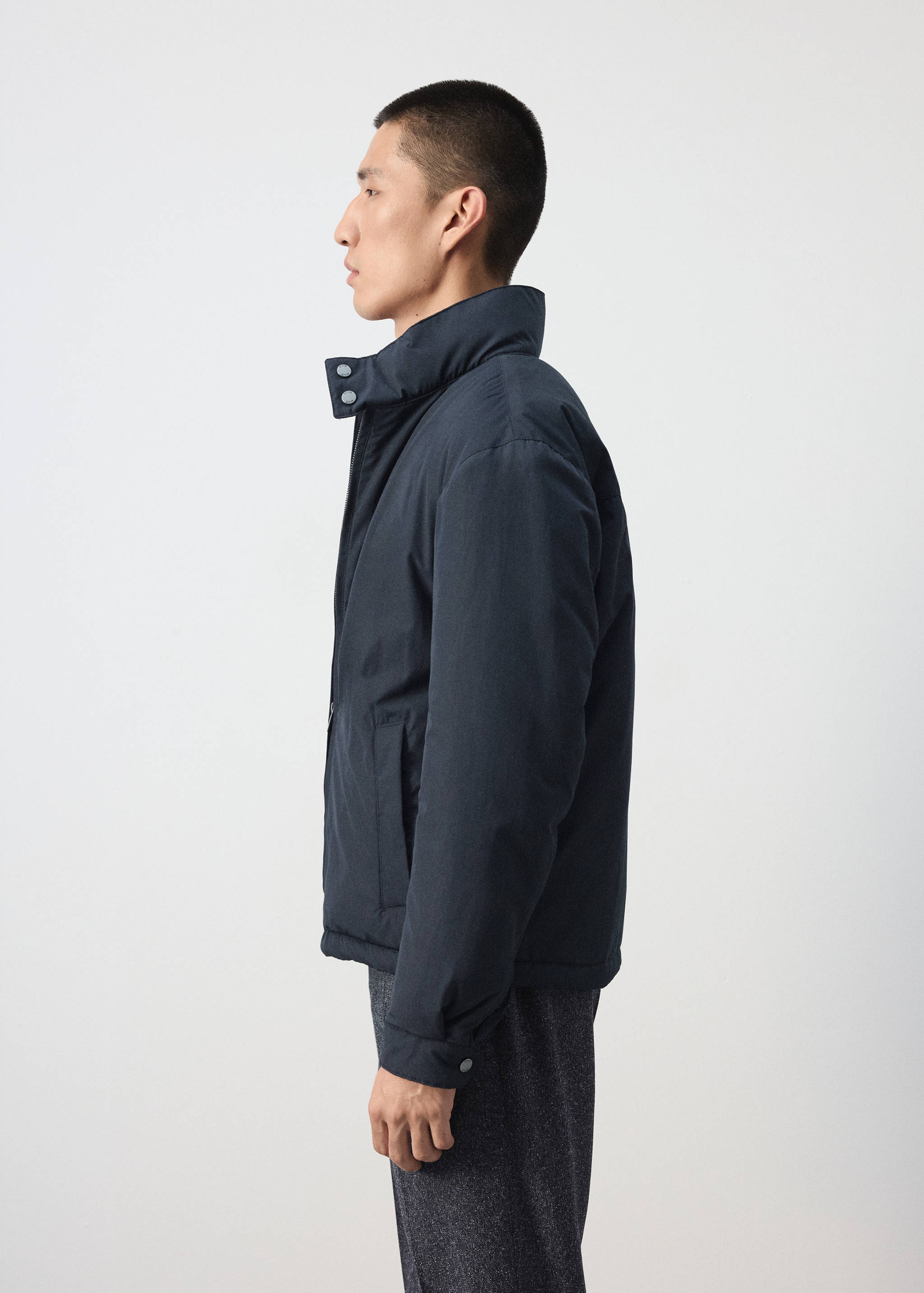 Navy blue jacket with a high collar and snap fastening.