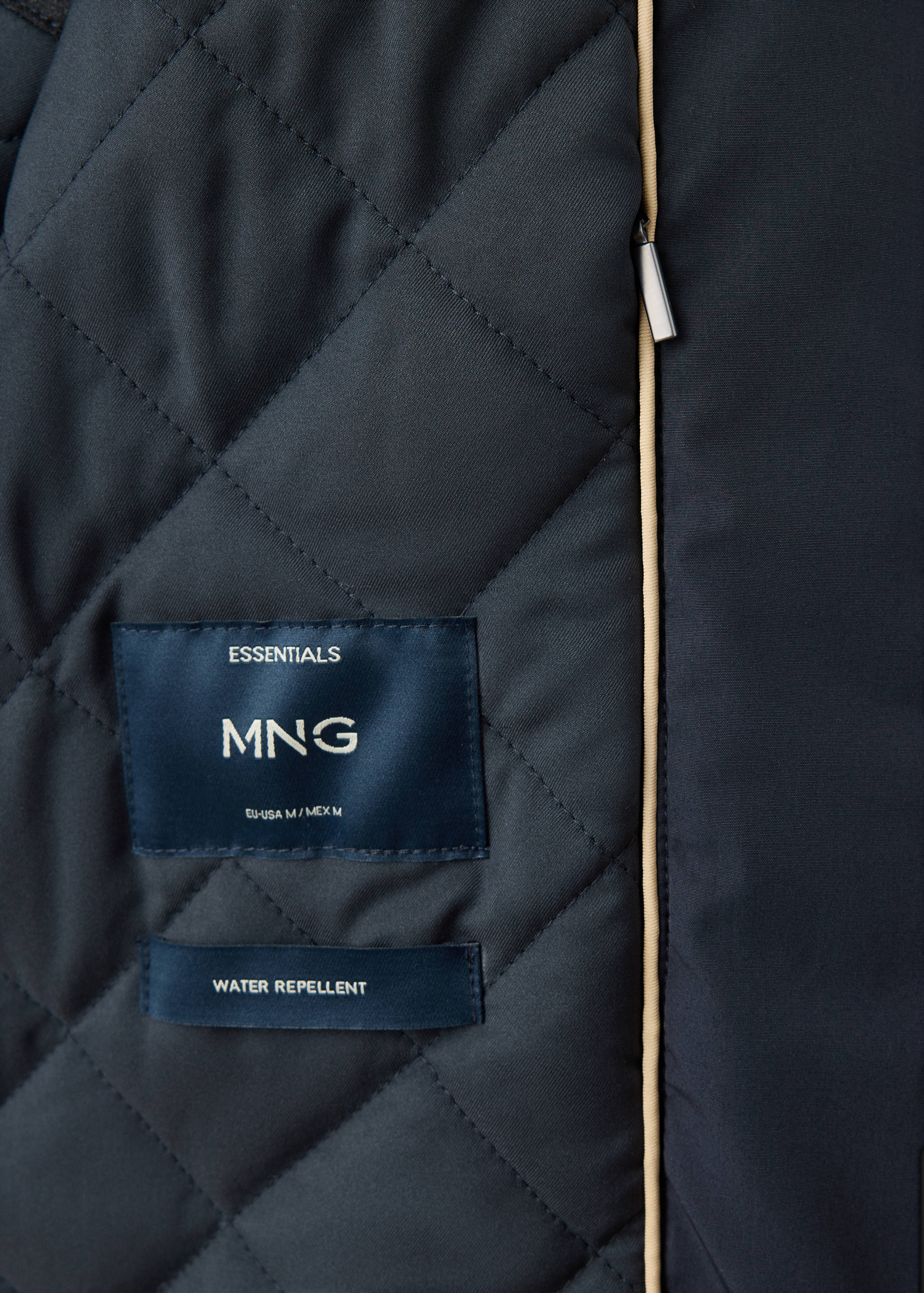 Close-up of a navy quilted jacket interior with brand labels and water-repellent detail.