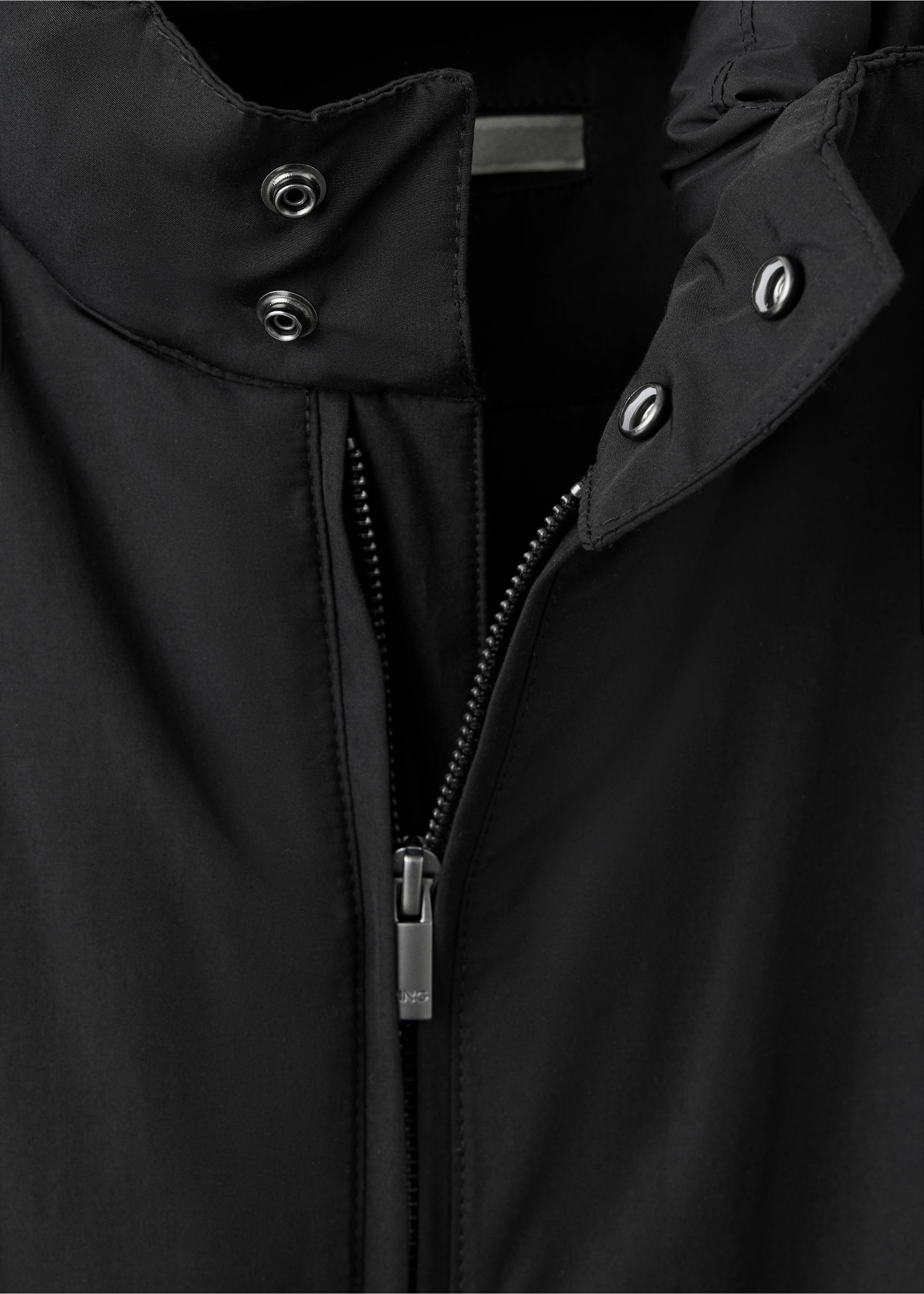 Detalle de un cuello de chaqueta negro con botones de presión y cierre de cremallera., Negro. Ref: 37057884-00.
