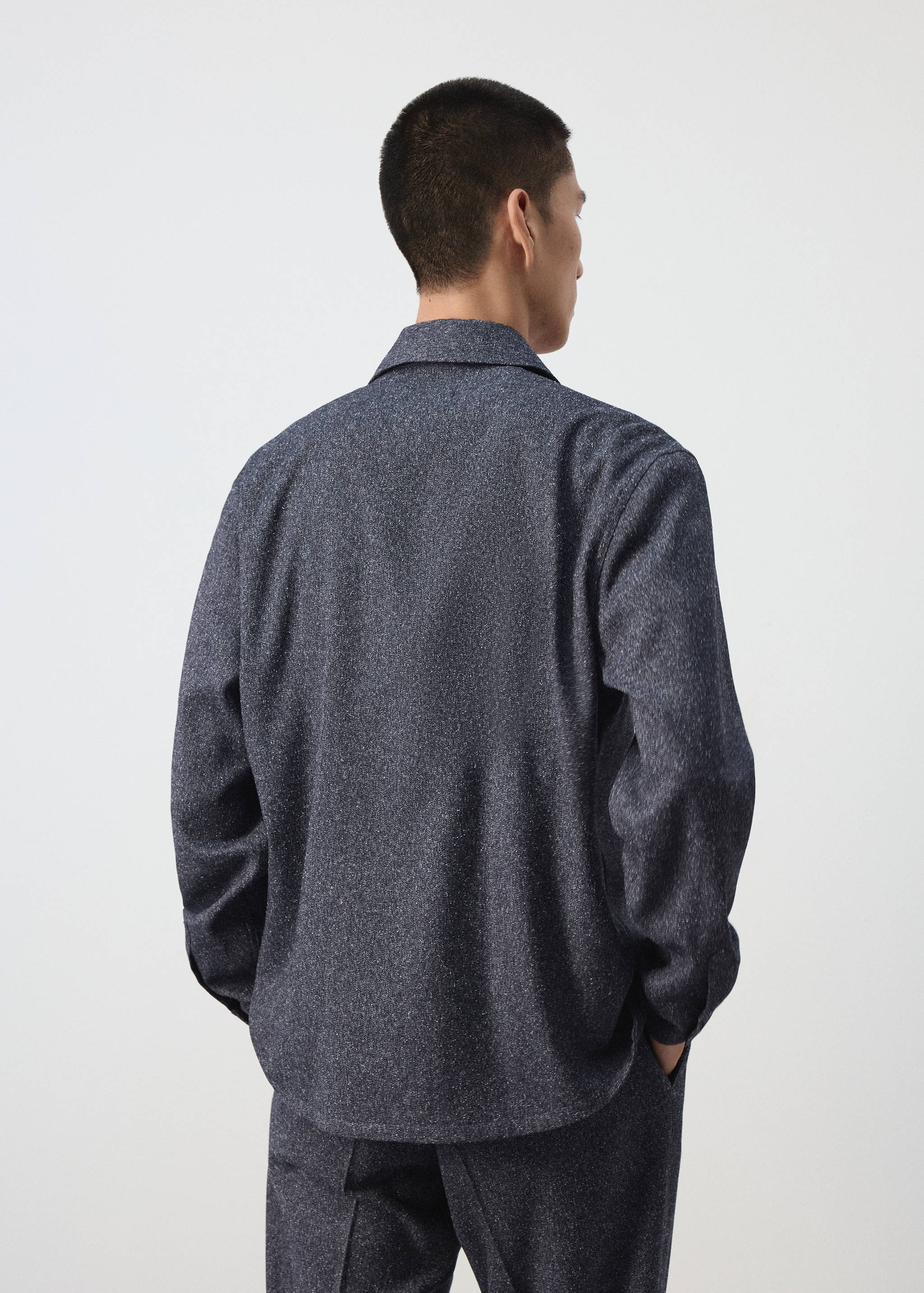 Dark grey textured overshirt seen from the back, worn with matching trousers.