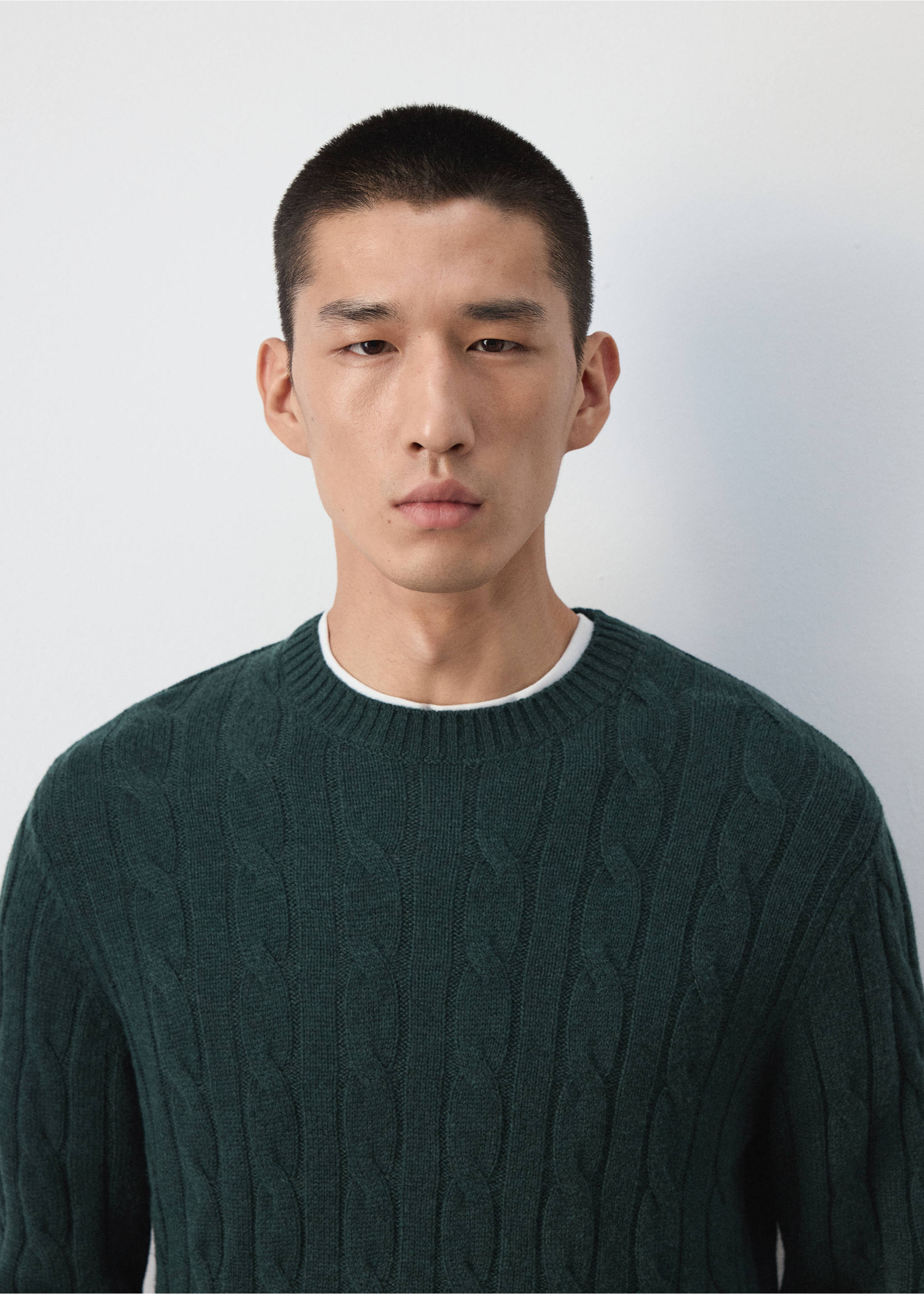 Close-up of a dark green cable-knit crew neck sweater worn by a model., Dark Green. Ref: 37057886-00.