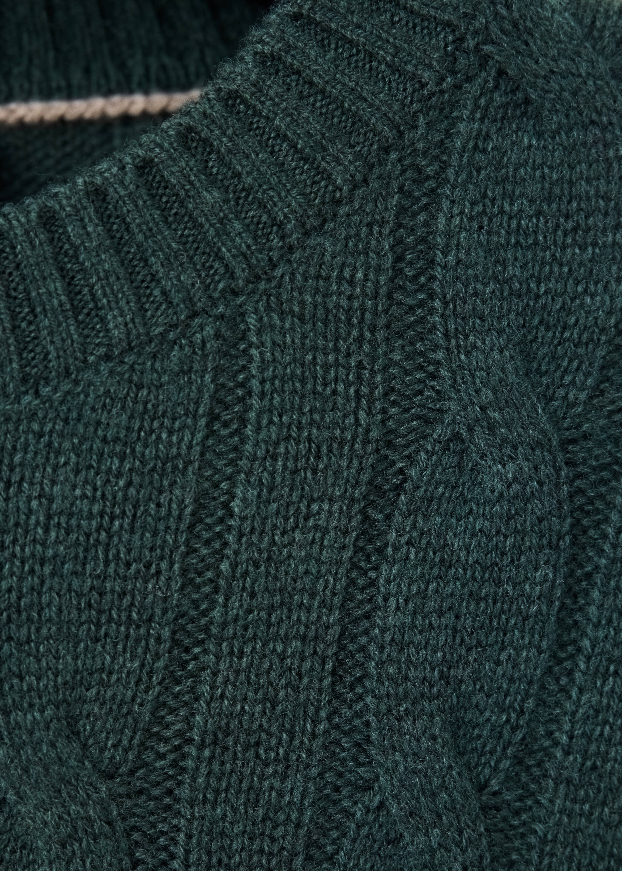 Close-up of a dark green cable-knit sweater neckline.