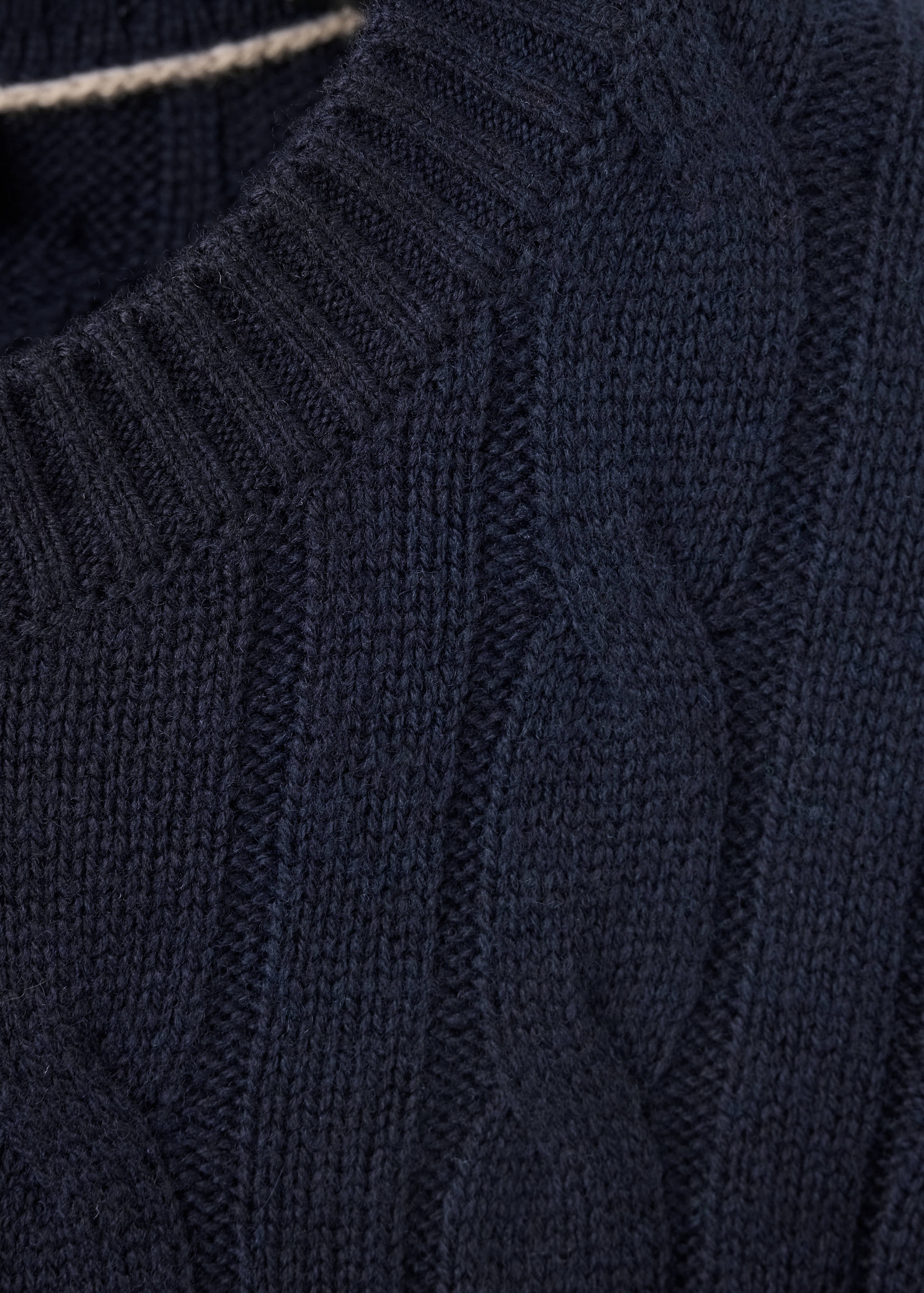 Close-up of a navy blue cable-knit jersey with a ribbed crew neck.