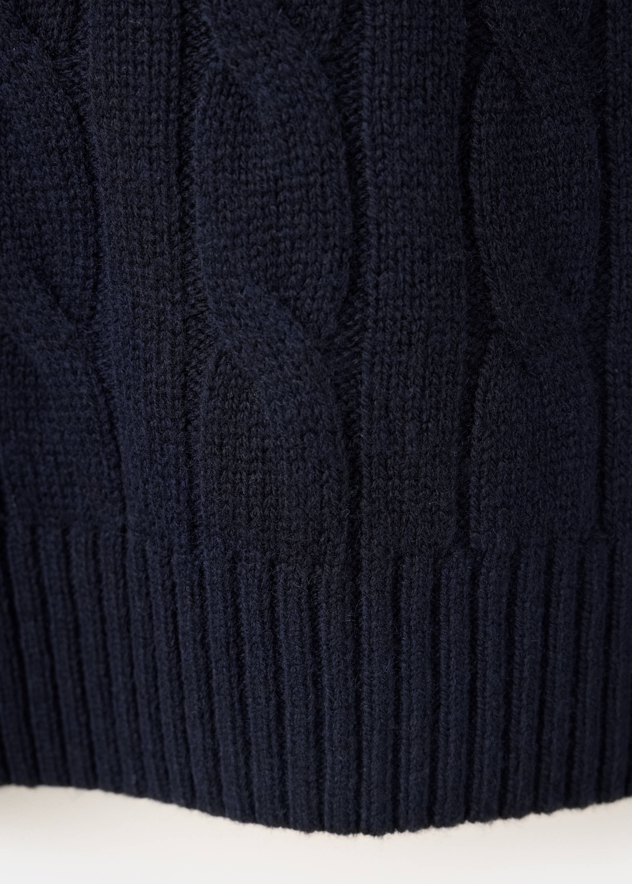 Close-up of navy blue men's cable-knit sweater fabric.