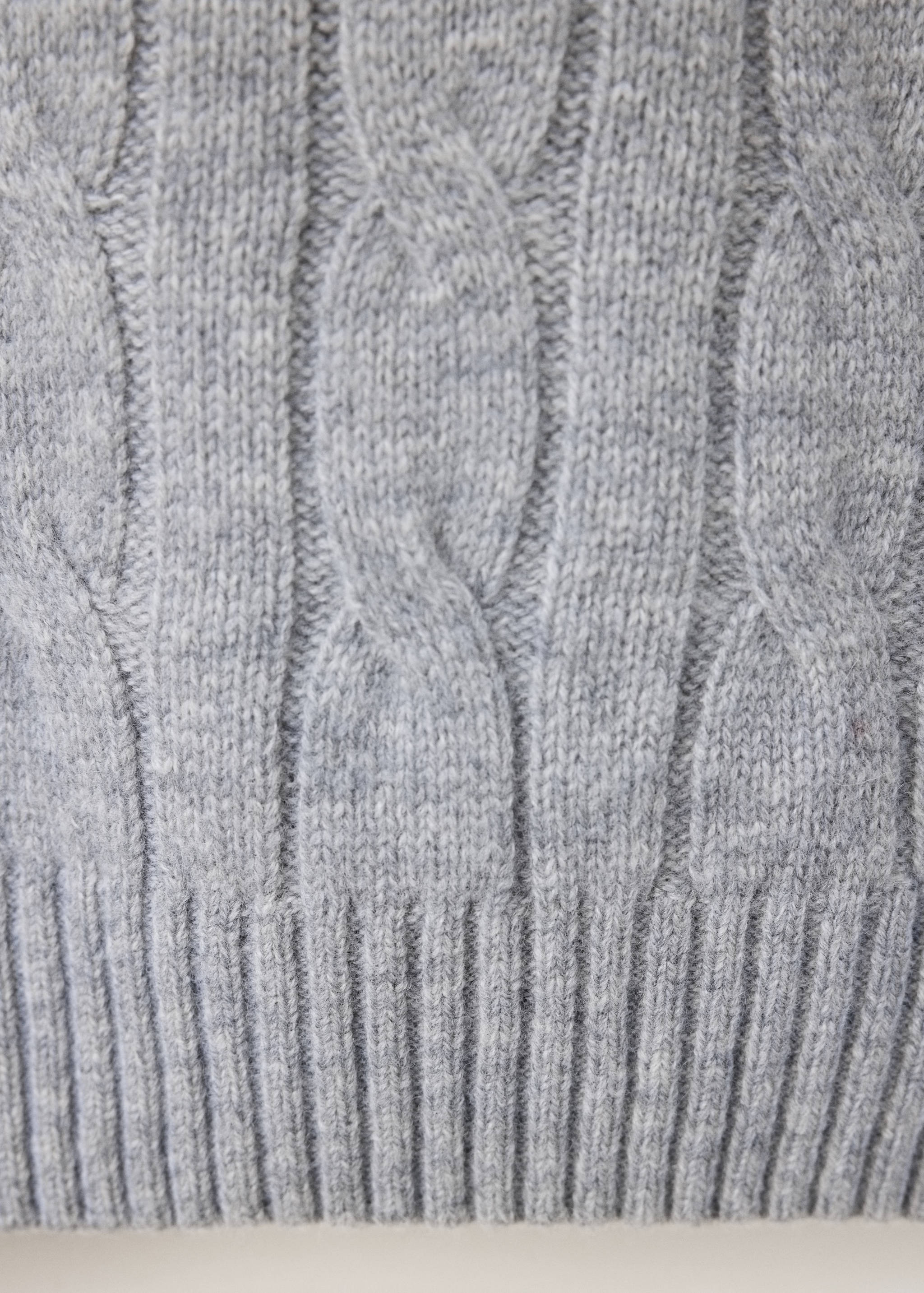 Grey knitted jumper fabric detail, showing a cable-knit and ribbed texture.