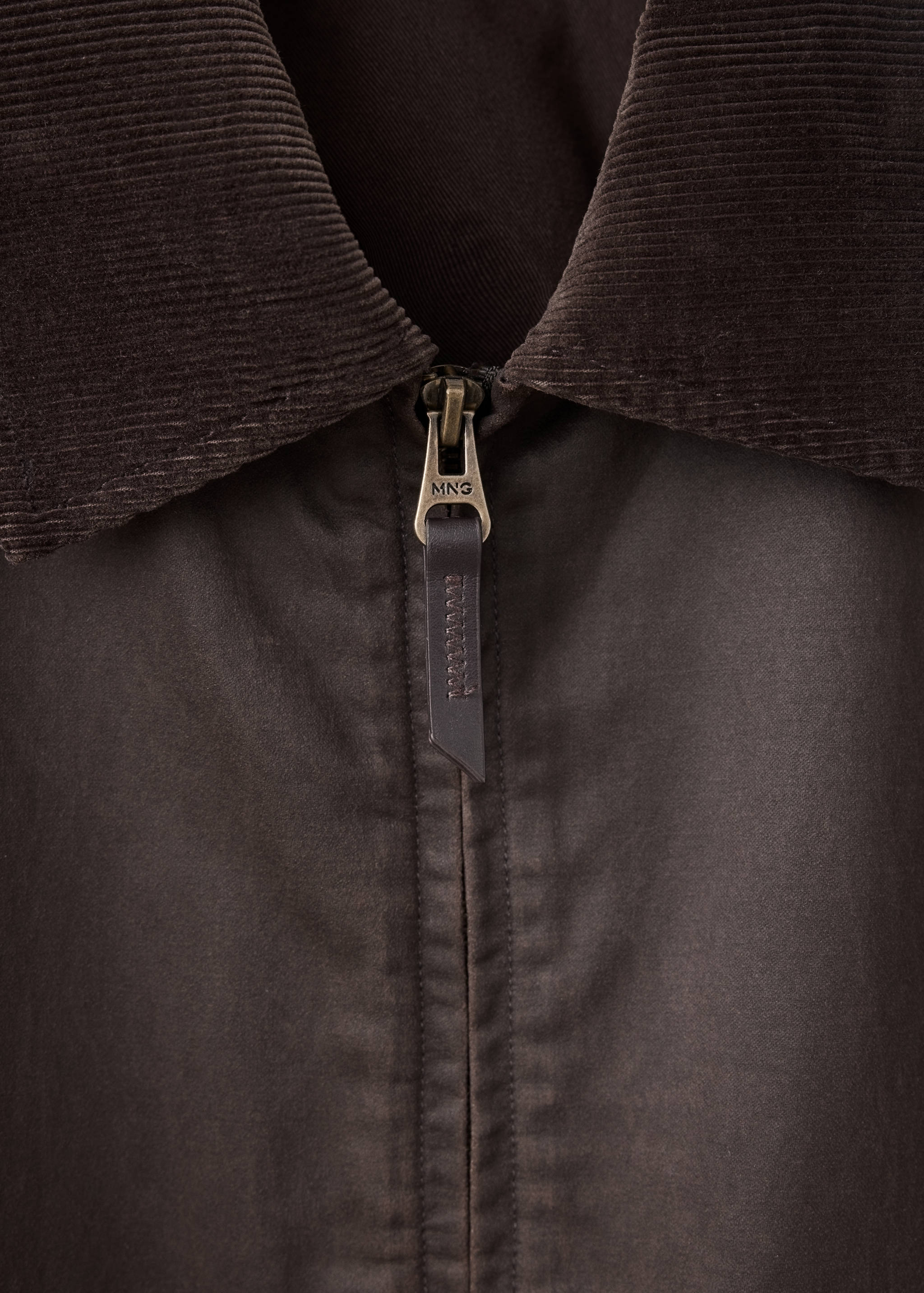 Close-up of a dark brown jacket featuring a corduroy collar and metal zip detail.
