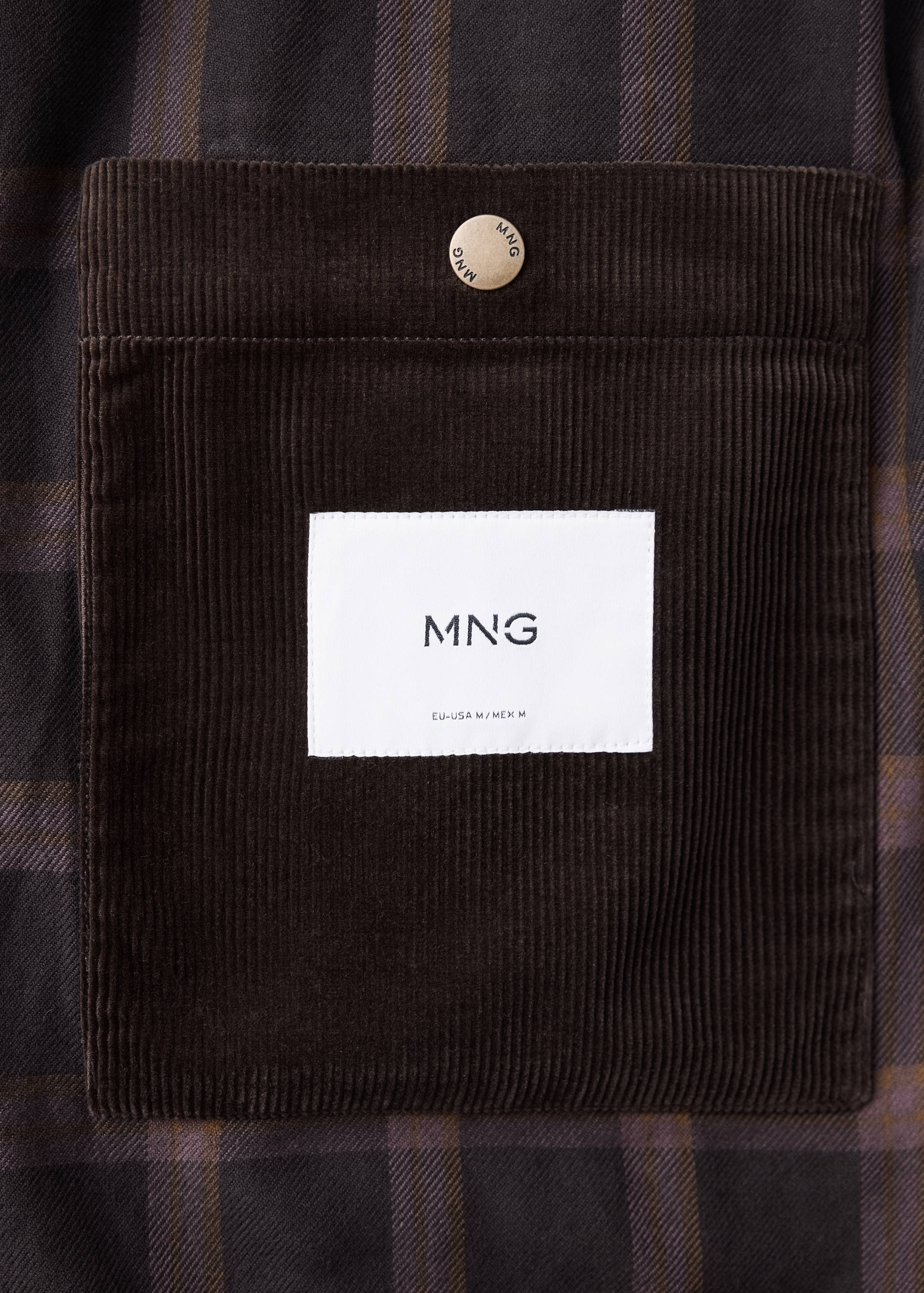 Close-up of a plaid jacket with a corduroy chest pocket and branded label.