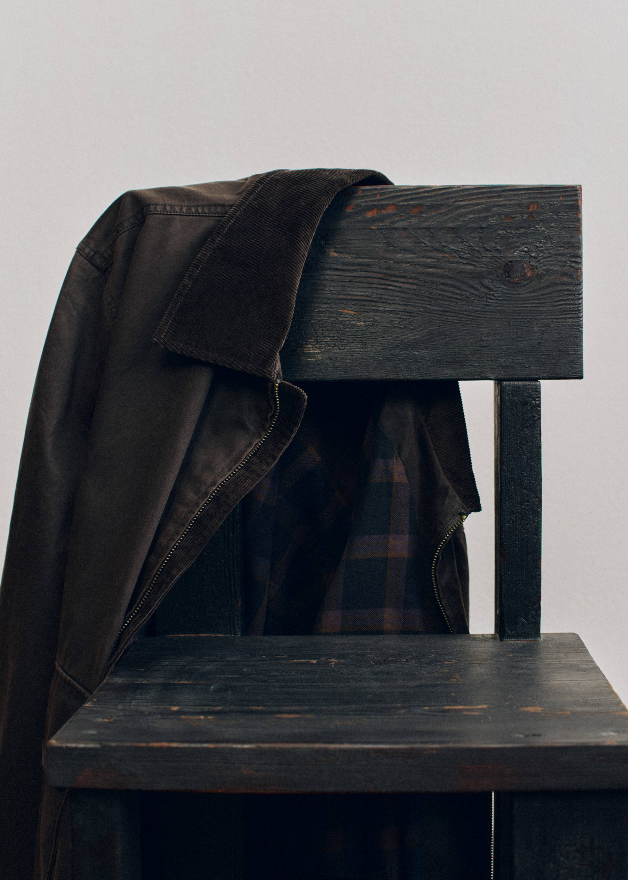 Dark brown jacket with a corduroy collar and plaid lining.