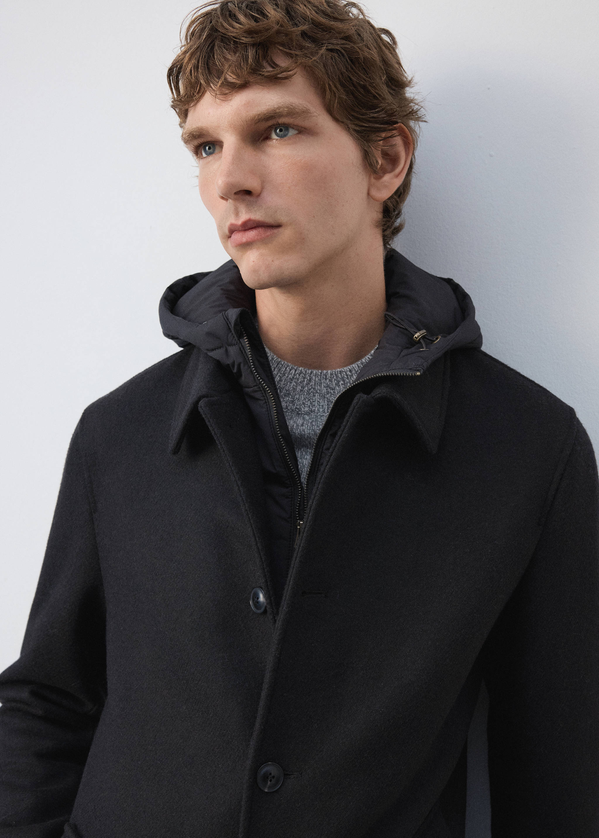 Close-up of a black coat with a collar and layered padded inner vest.