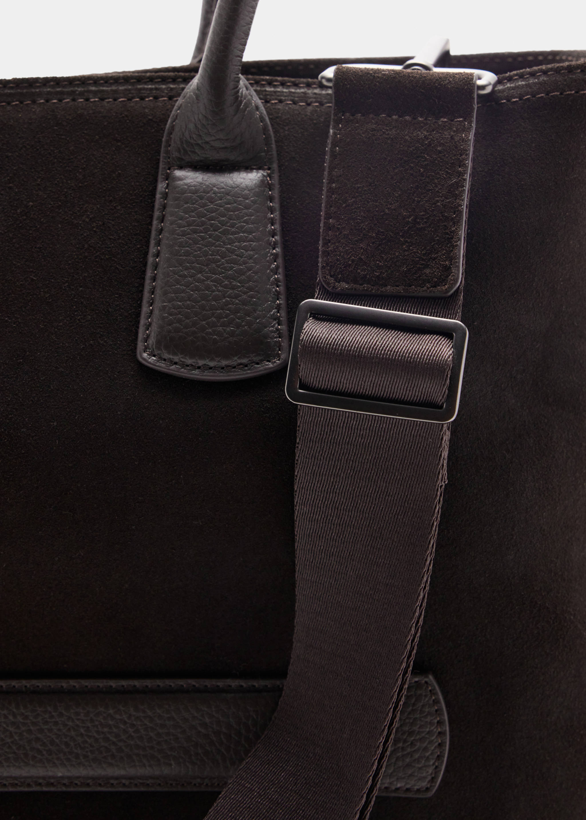 Close-up of a dark brown suede bowling bag with an adjustable strap.