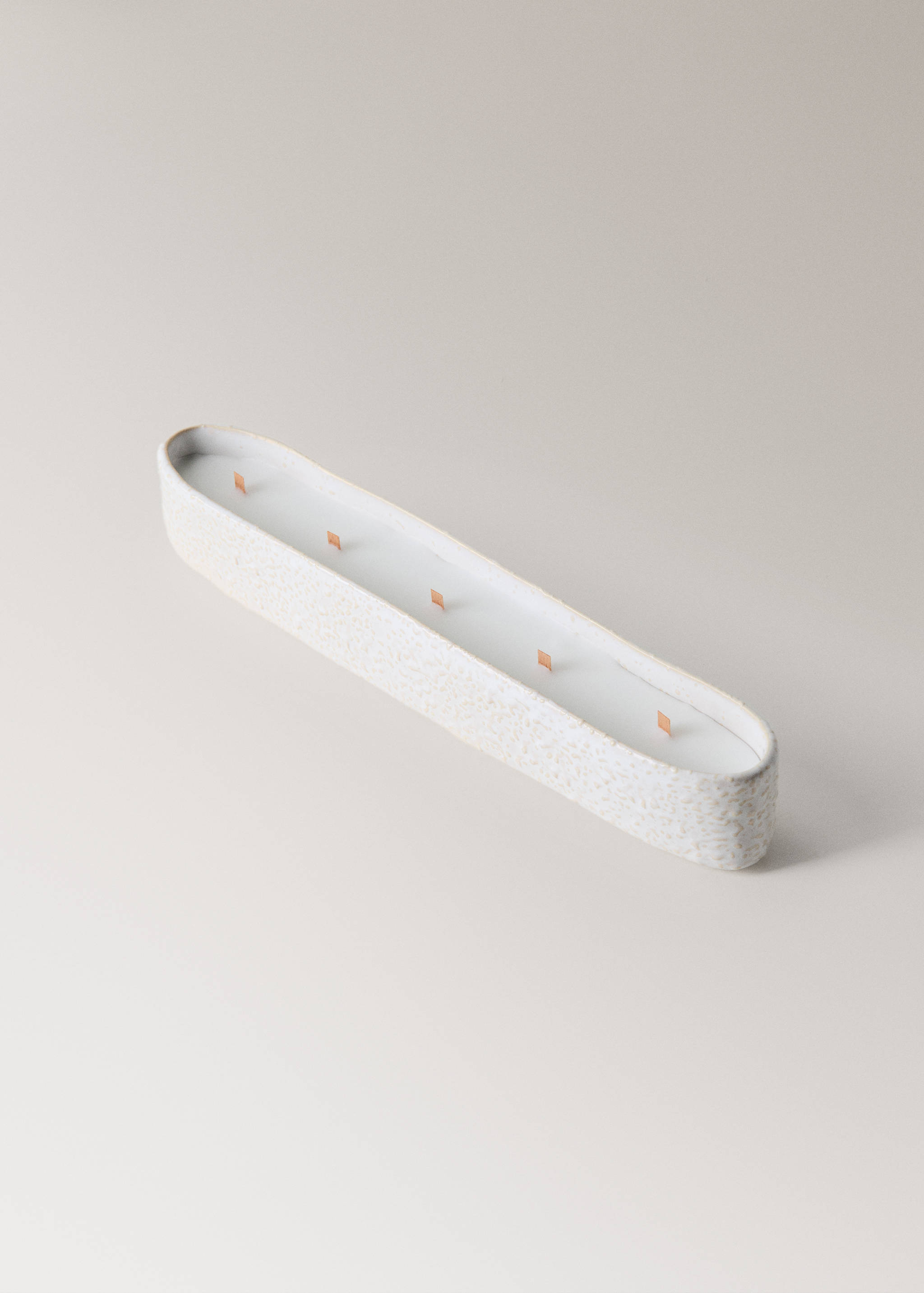 Long oval candle in an off-white speckled container with five wooden wicks.
