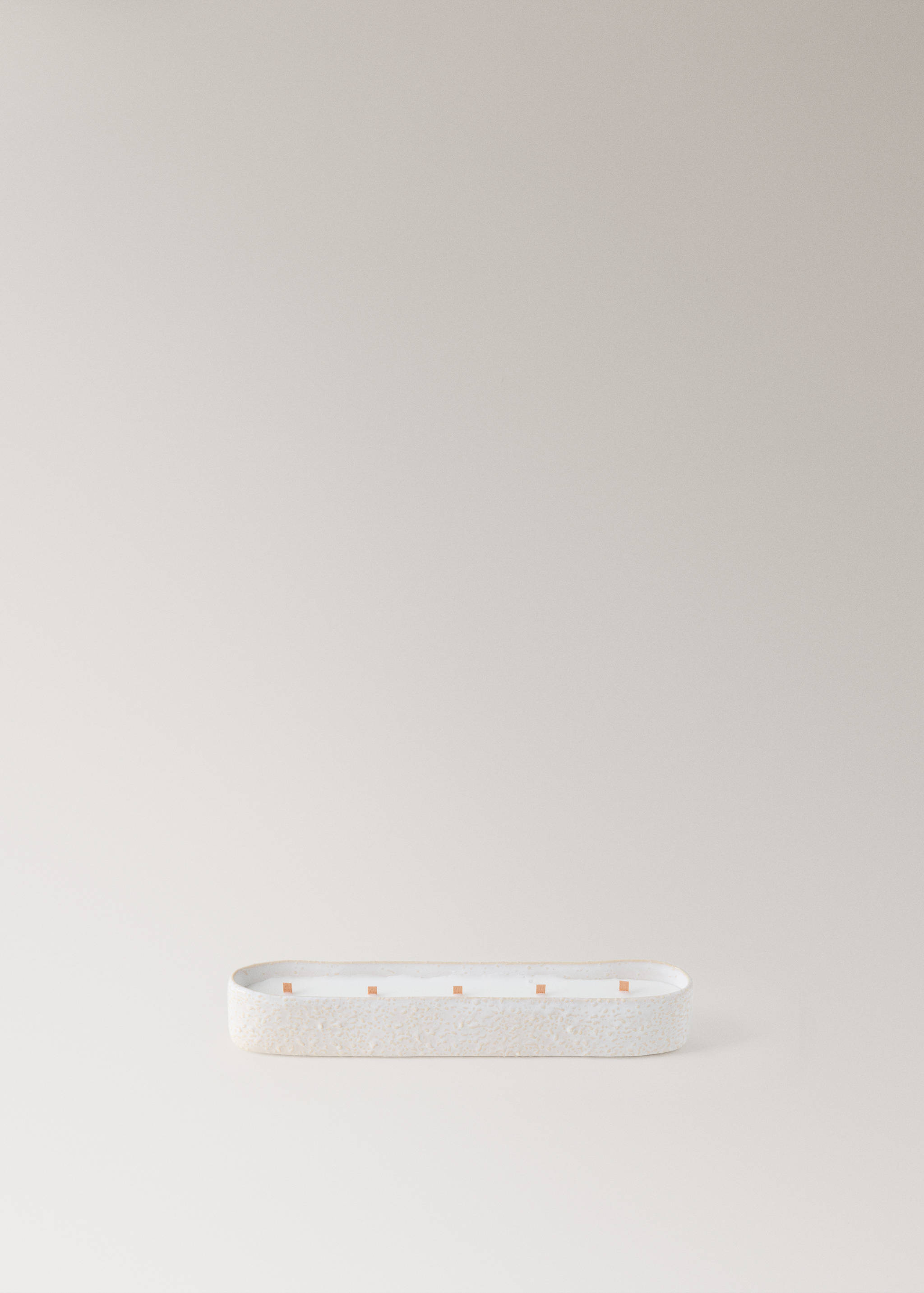 Long oval candle in a textured light beige container with five wicks.