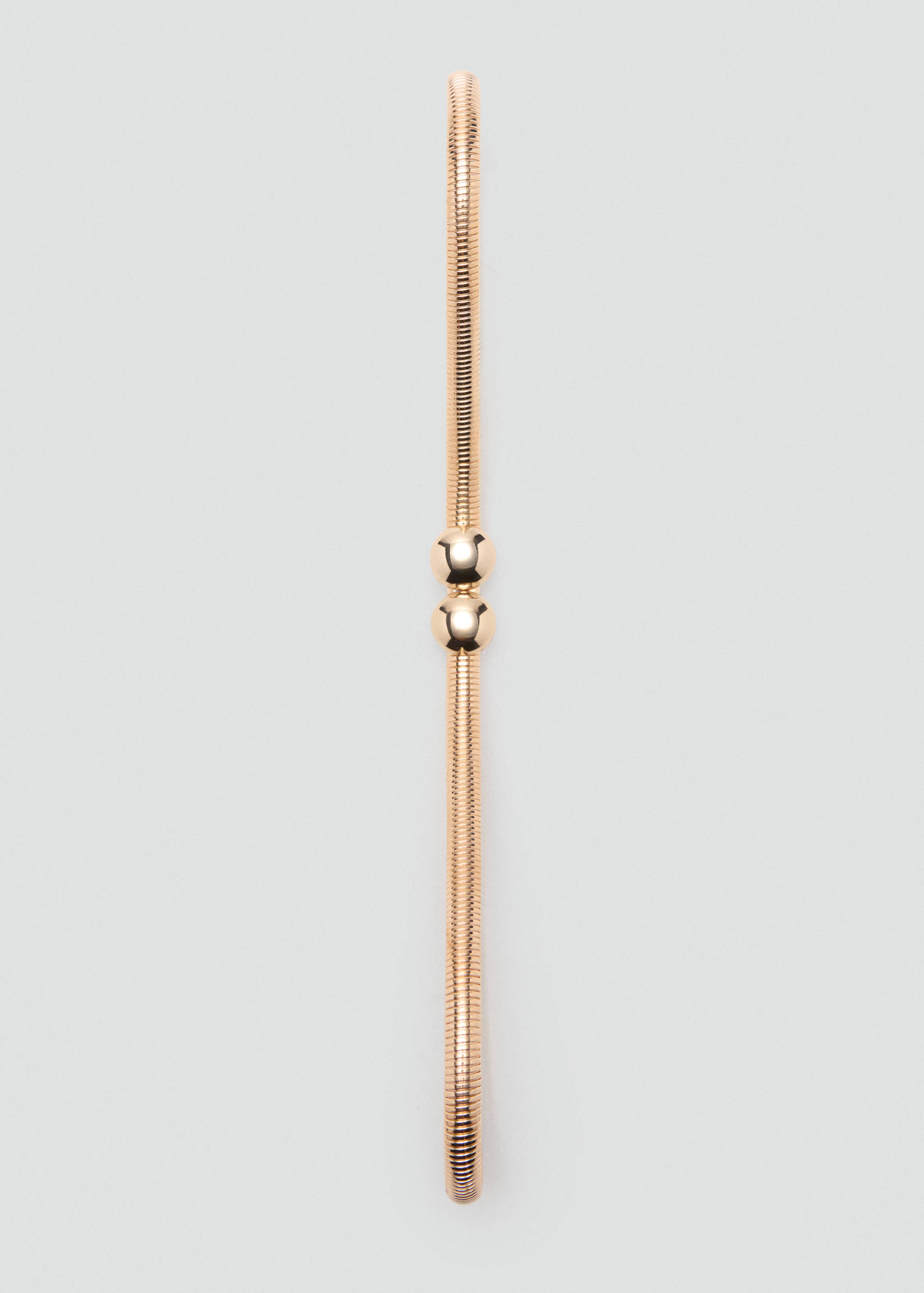 Close-up of a gold metallic snake-chain belt with two central spherical ball accents.