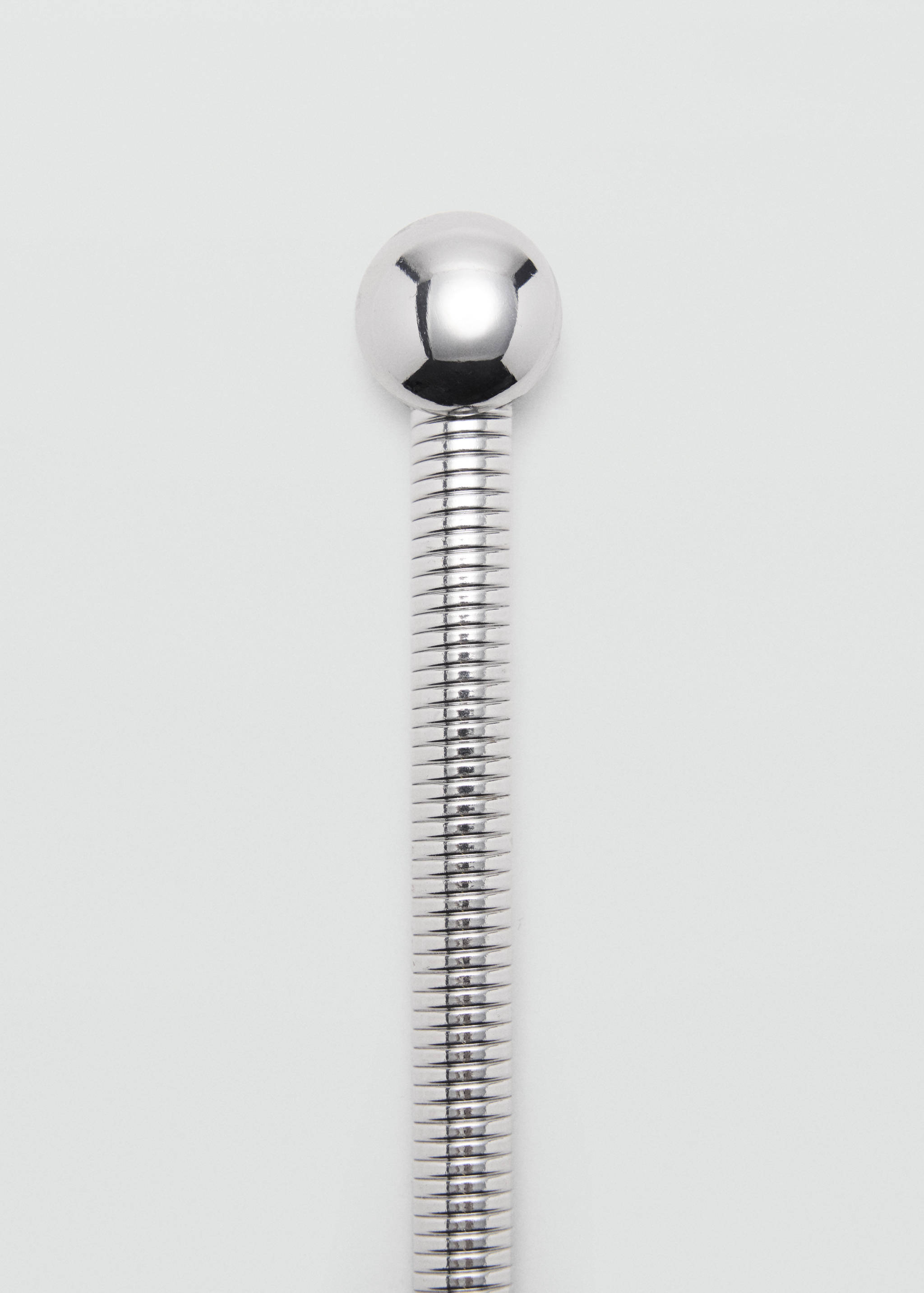 Silver-coloured metal belt detail featuring a flexible tubular band and a spherical ball terminal.