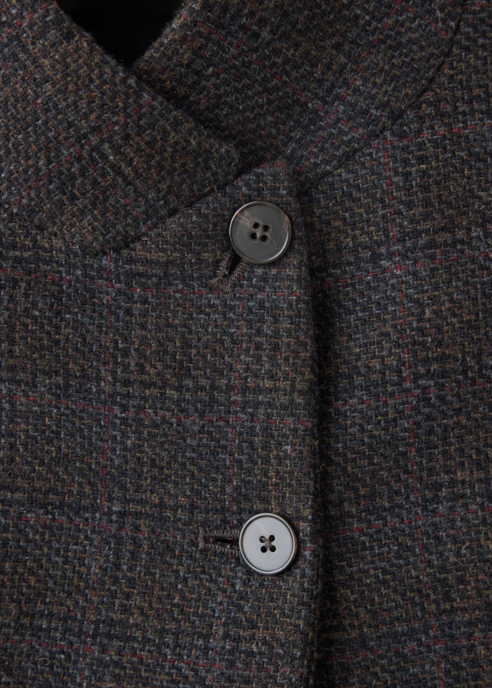 Detalle de la americana de tweed que muestra los botones delanteros y el cuello.