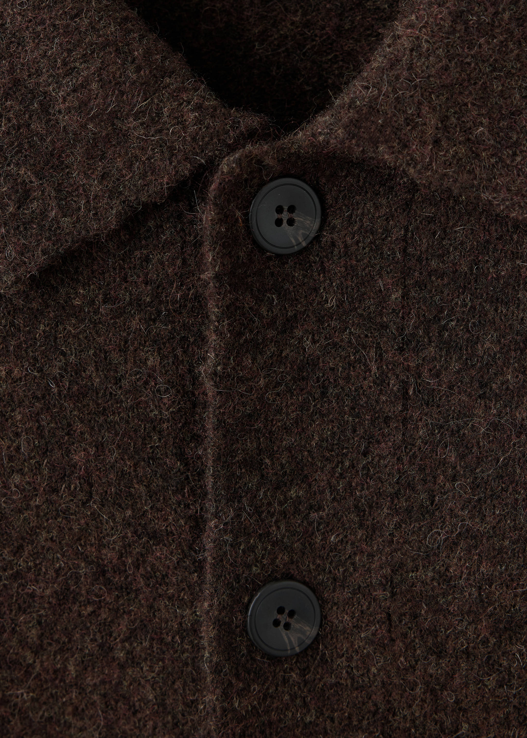 Close-up of a dark brown textured shirt collar and button placket.