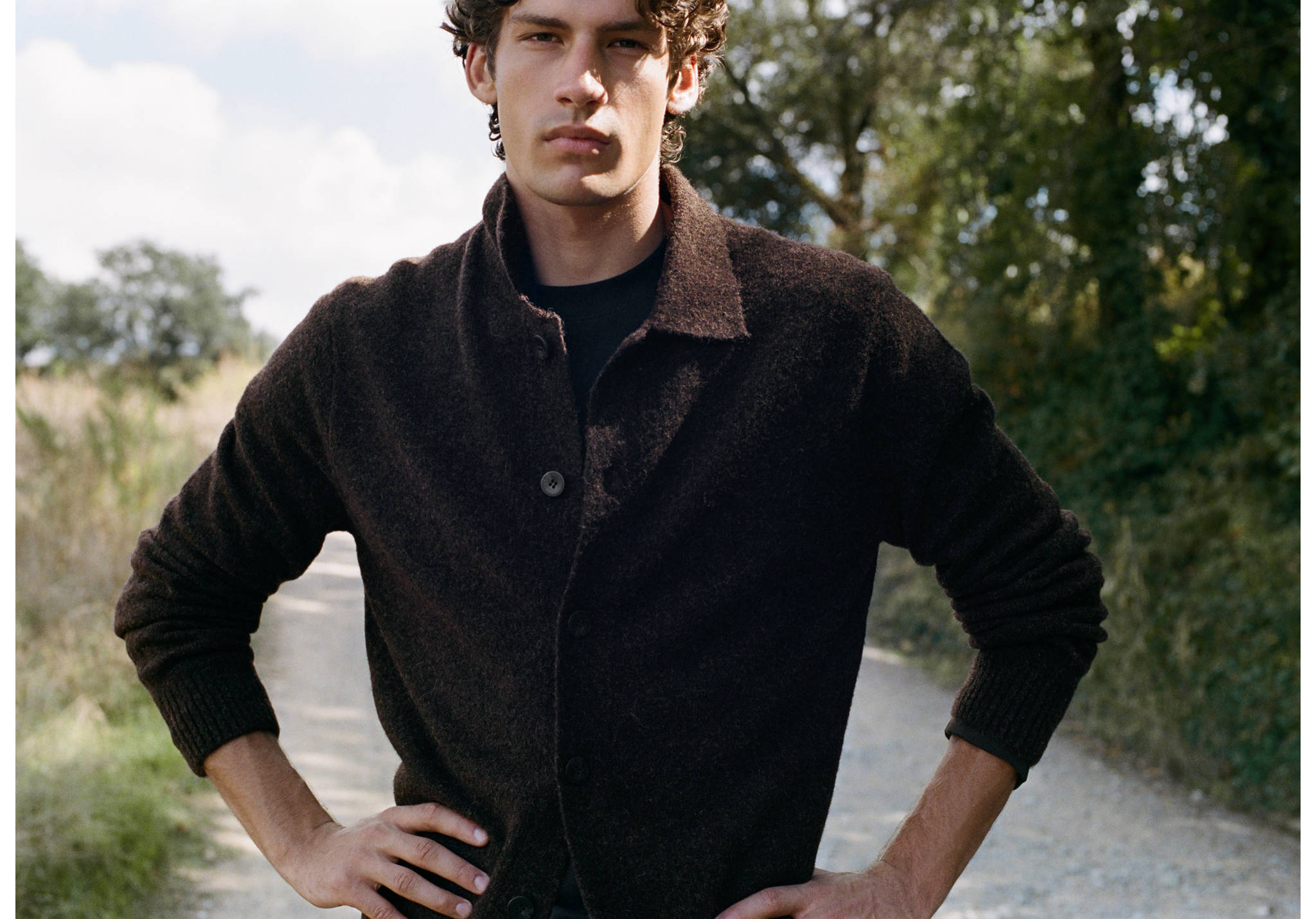 Dark brown knitted shirt with long sleeves and a collar worn outdoors.