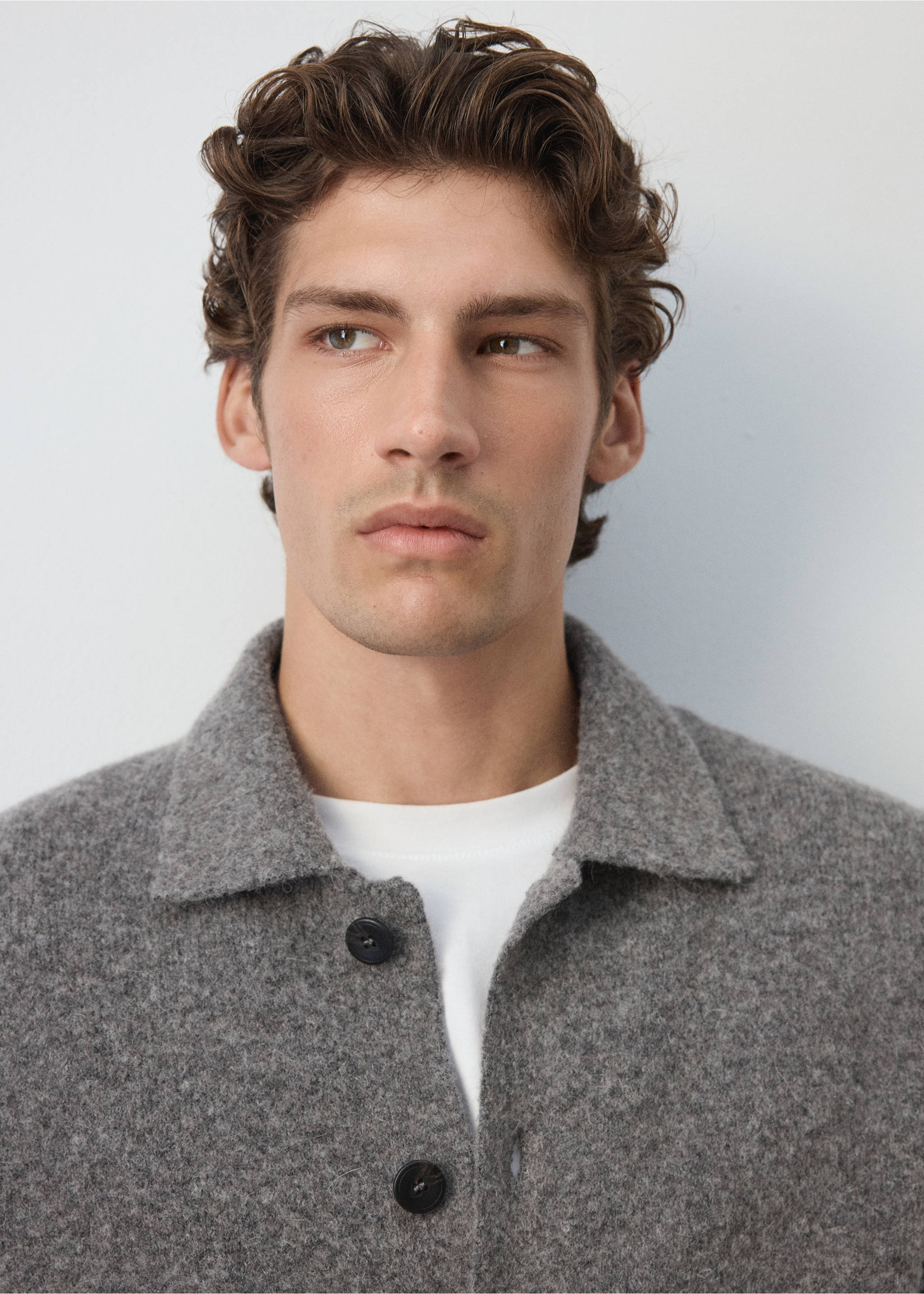 Close-up of a grey textured shirt with a collar and dark buttons worn over a white t-shirt., Medium Brown. Ref: 37057916-00.