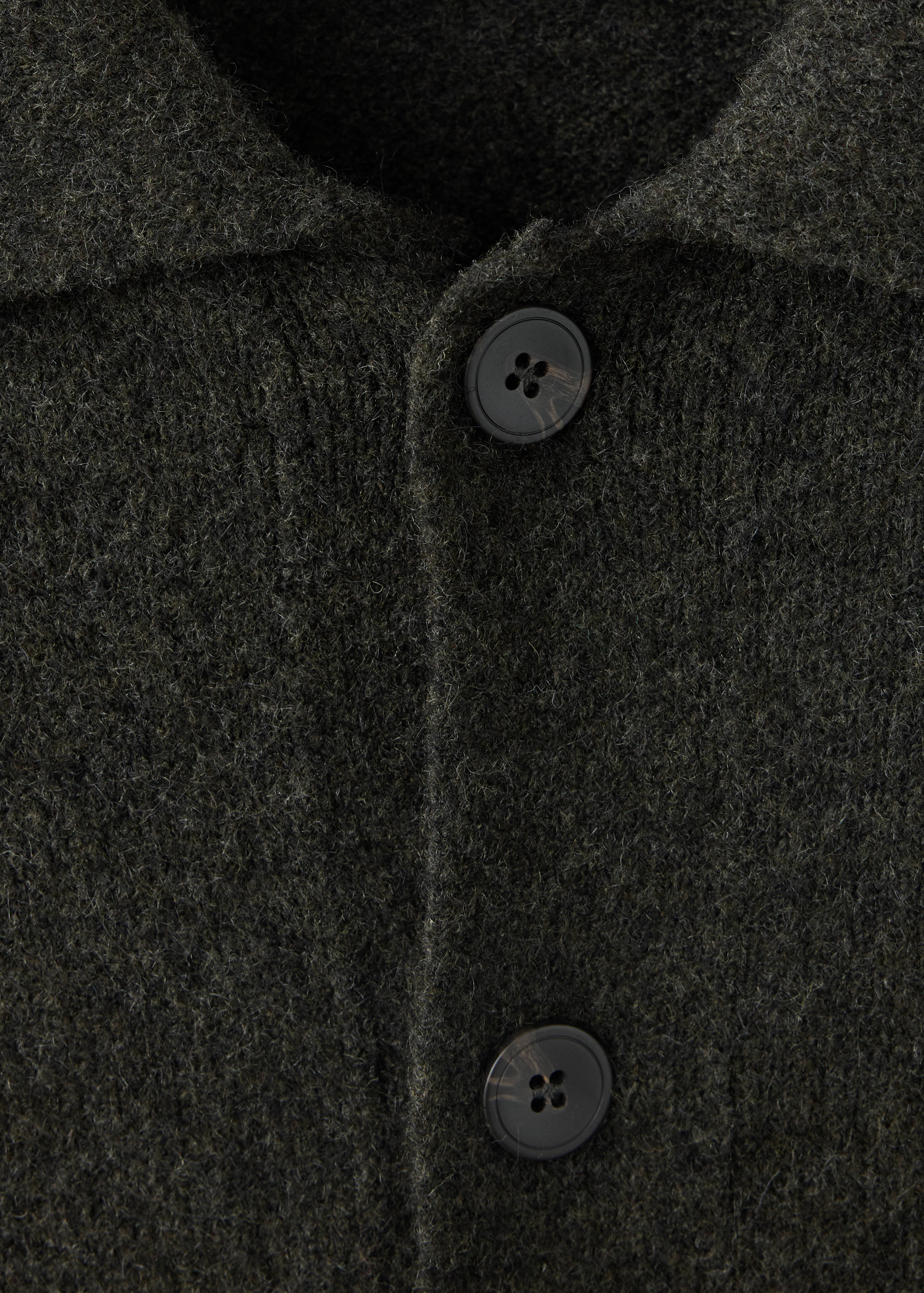 Dark green knitted shirt detail featuring a collar and button placket.