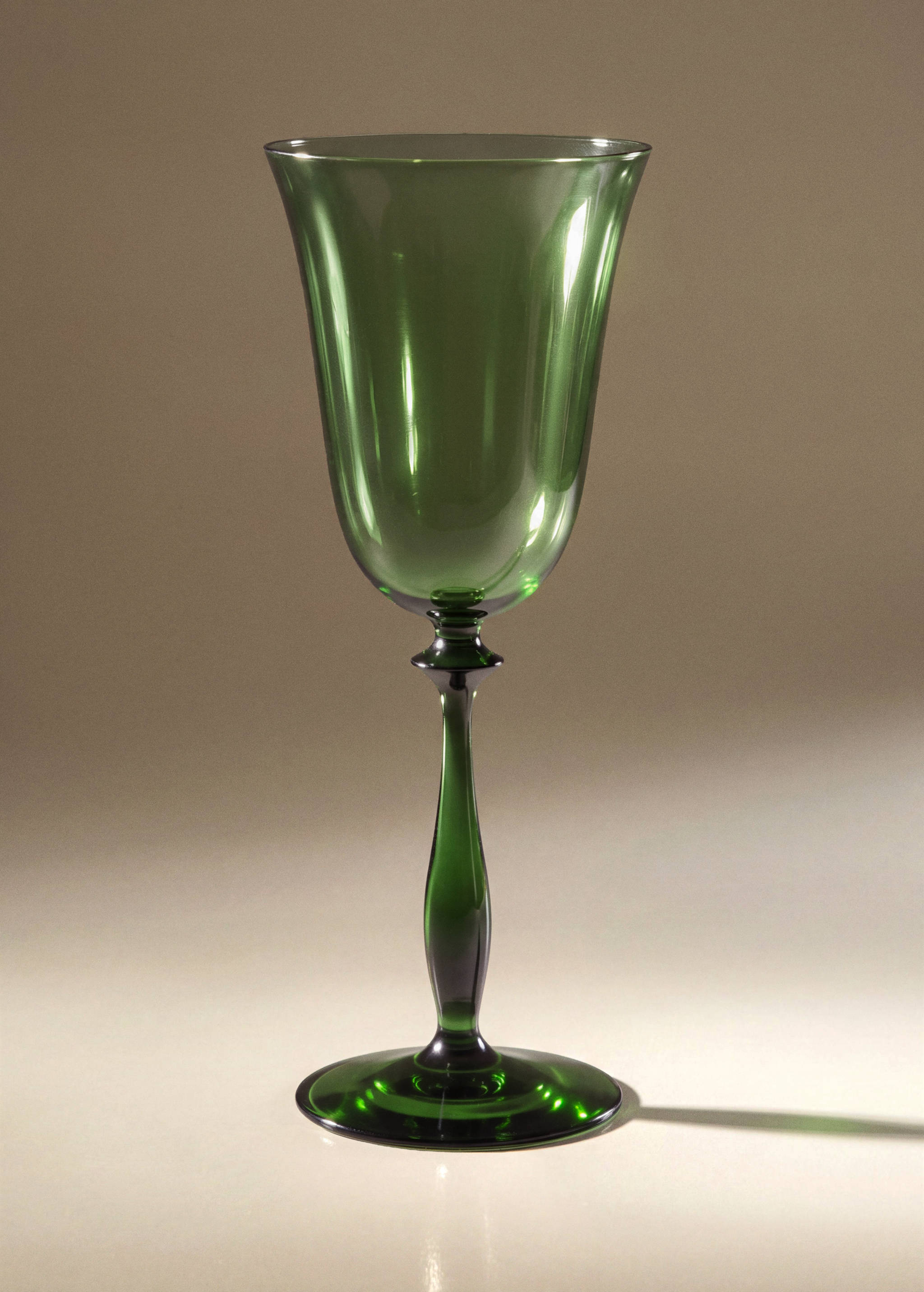 Green glass goblet with a slender stem and flared bowl.