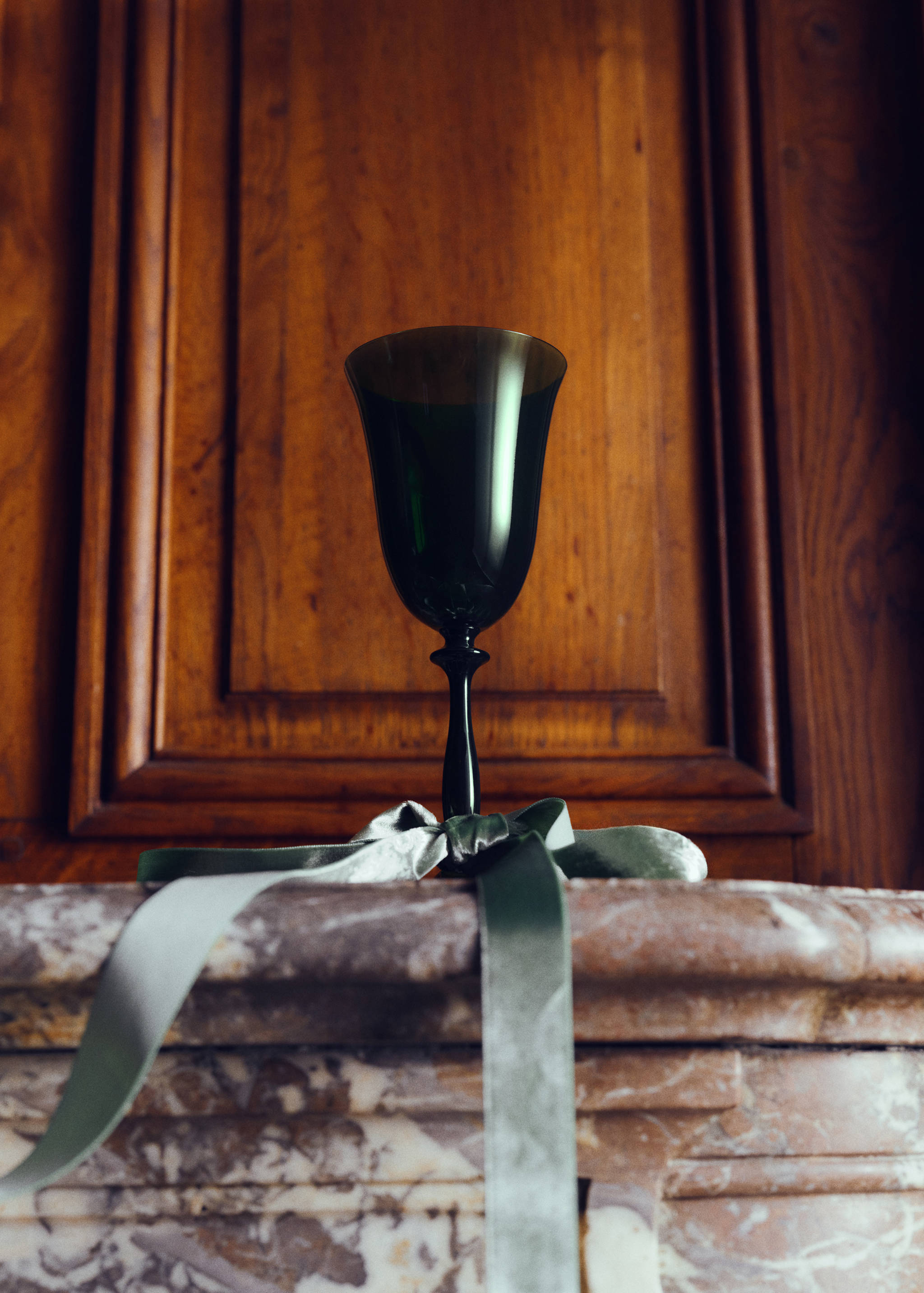 Dark green glass goblet tied with a sage green velvet ribbon.