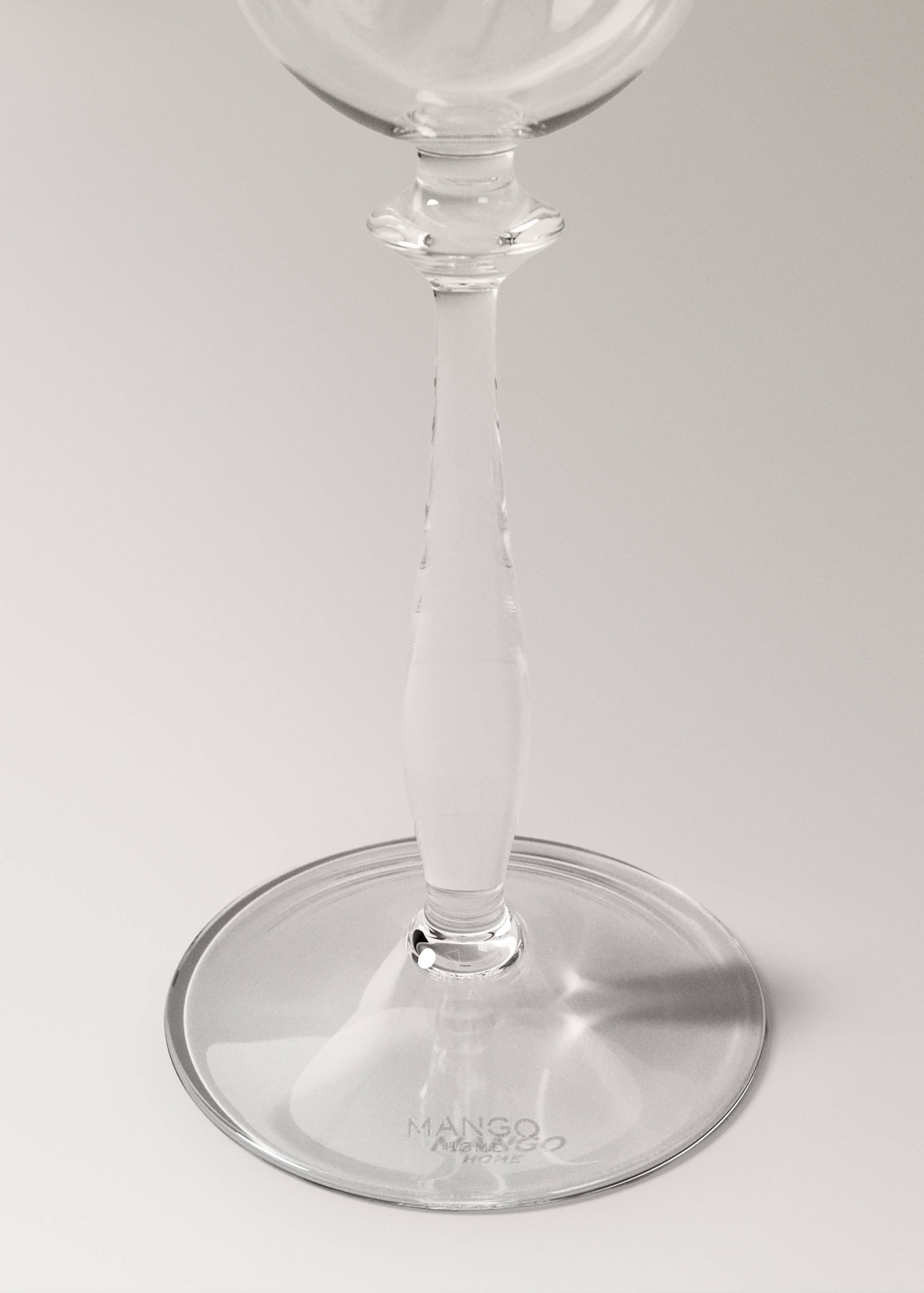 Clear glass goblet showing detail of its slender stem and wide base.