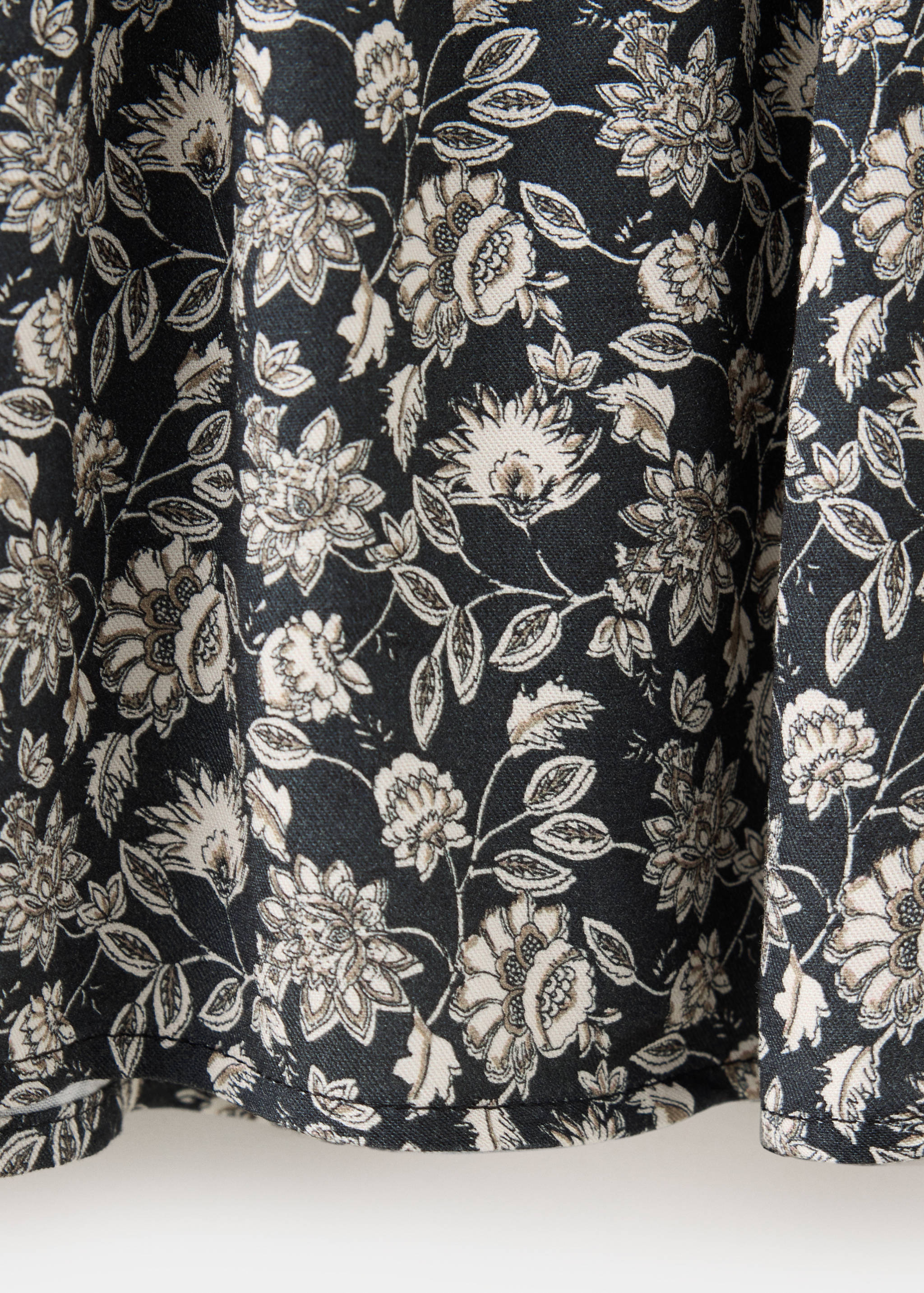 Close-up of the black dress fabric with a cream and grey floral print.