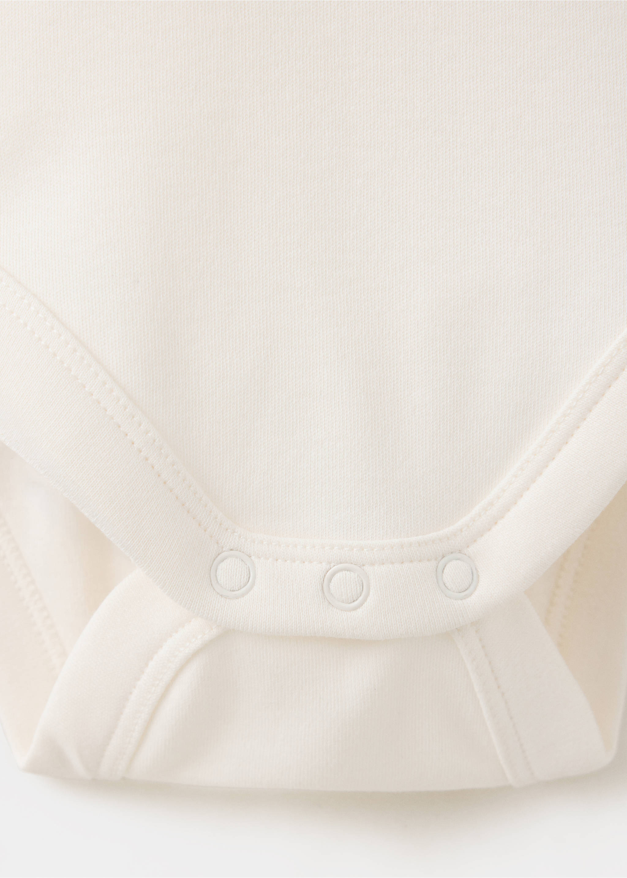 Close-up of fabric and snap button detail on an off-white baby body., Off White. Ref: 37057937-00.