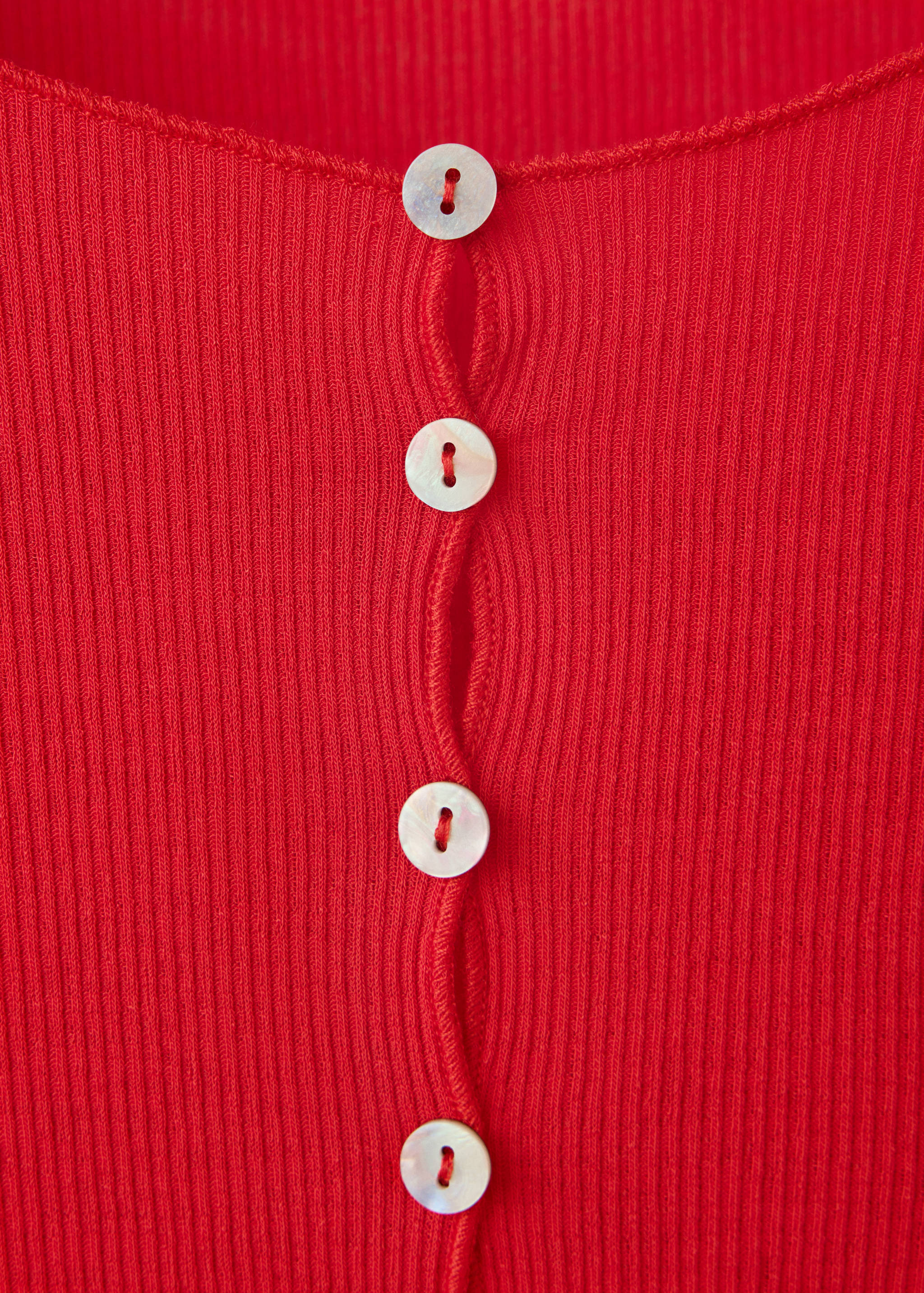 Close-up of a red ribbed t-shirt featuring a buttoned placket.