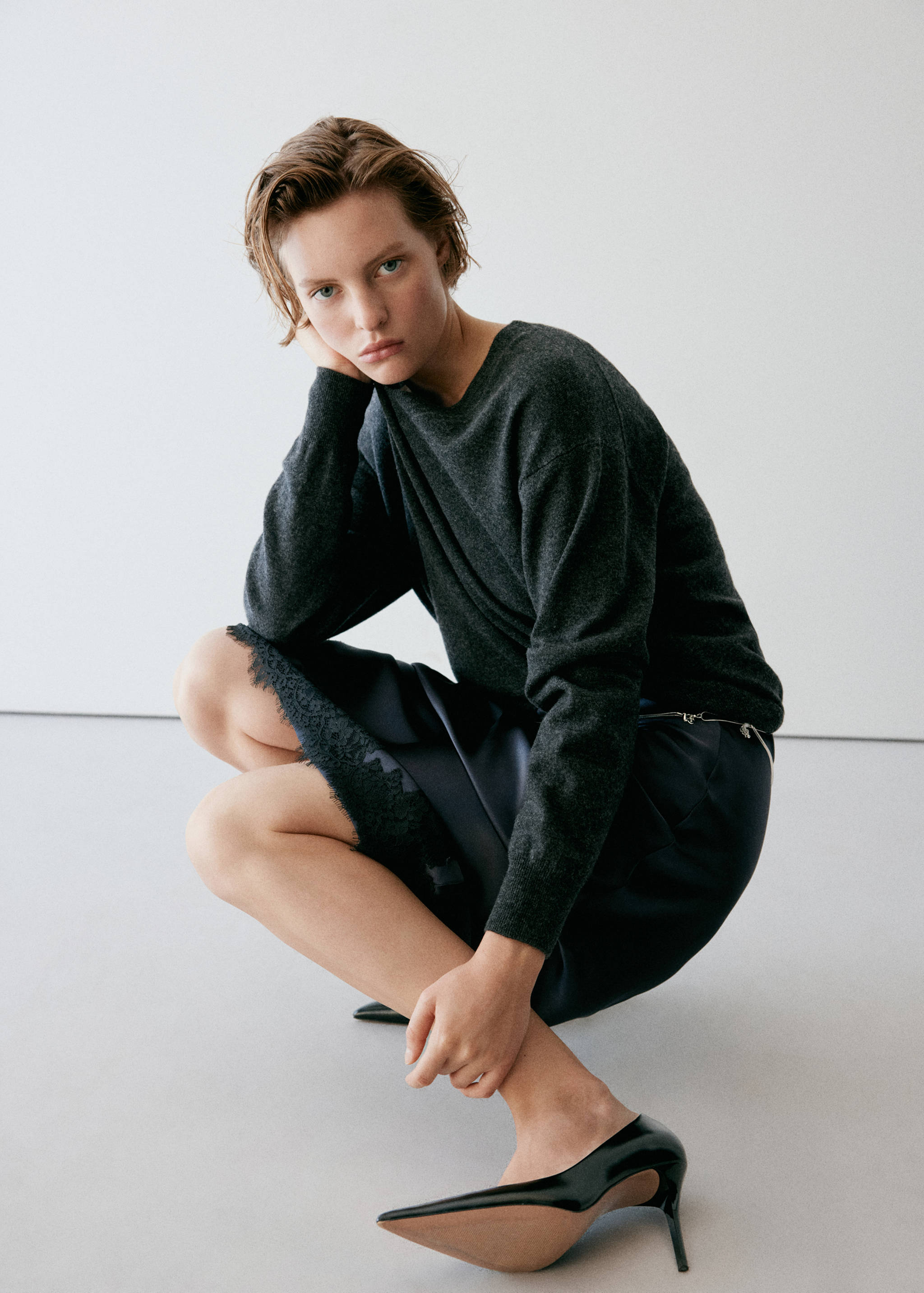 Dark satin skirt with a lace-trimmed hem, styled with a dark grey sweater.