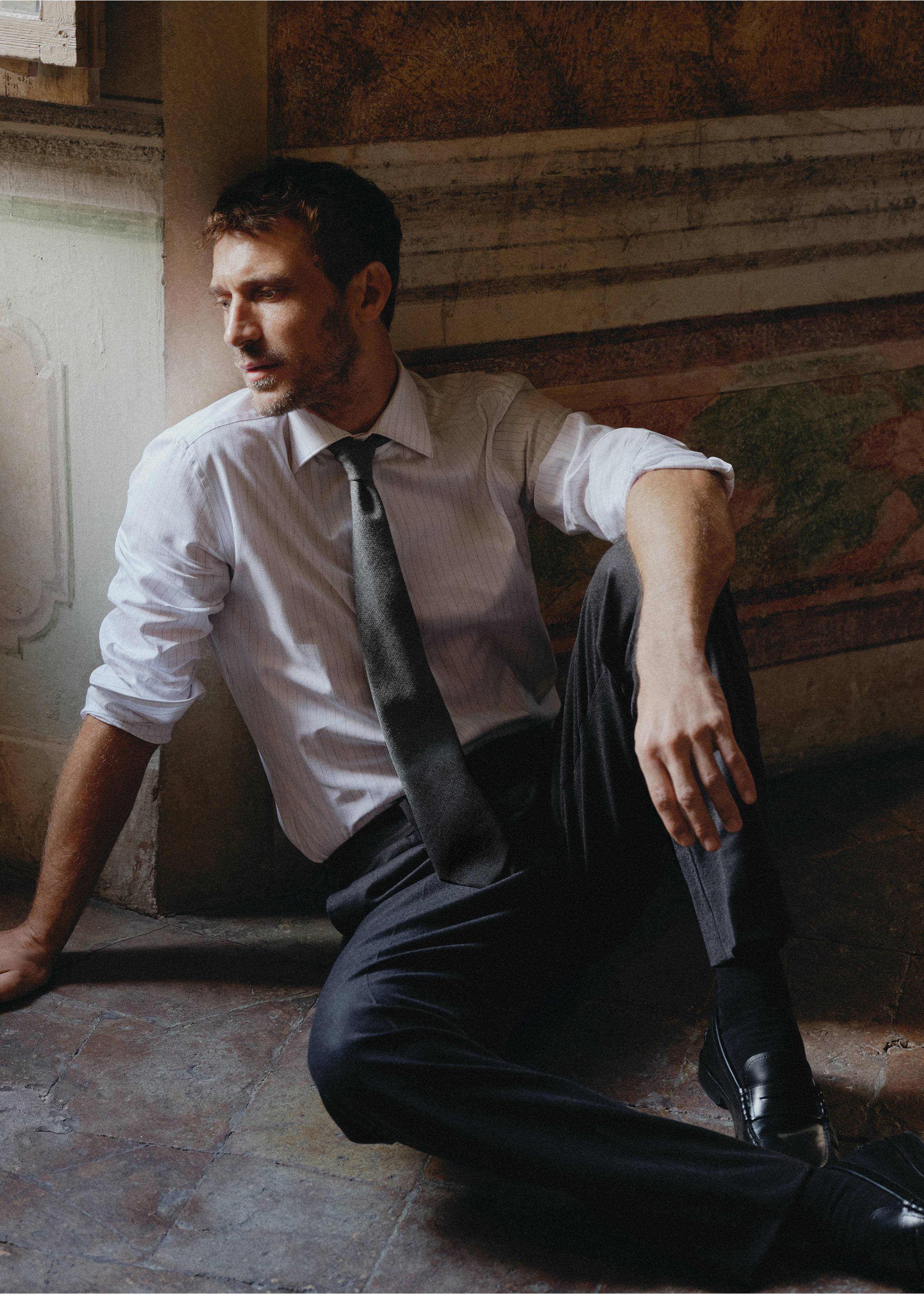 Dark grey tie worn by a seated model in a white shirt and trousers., Grey. Ref: 37057943-00.