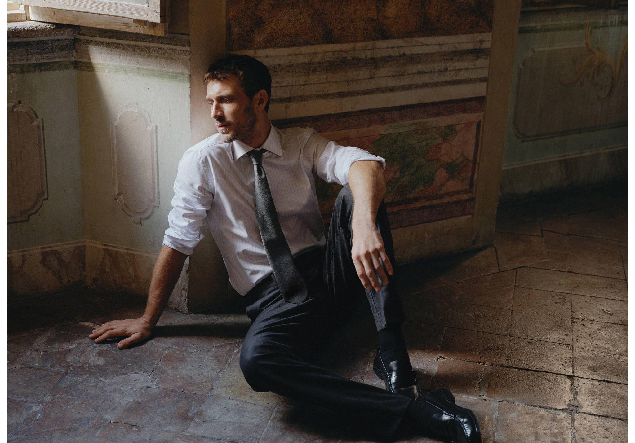 Dark grey tie worn with a light shirt and dark trousers.
