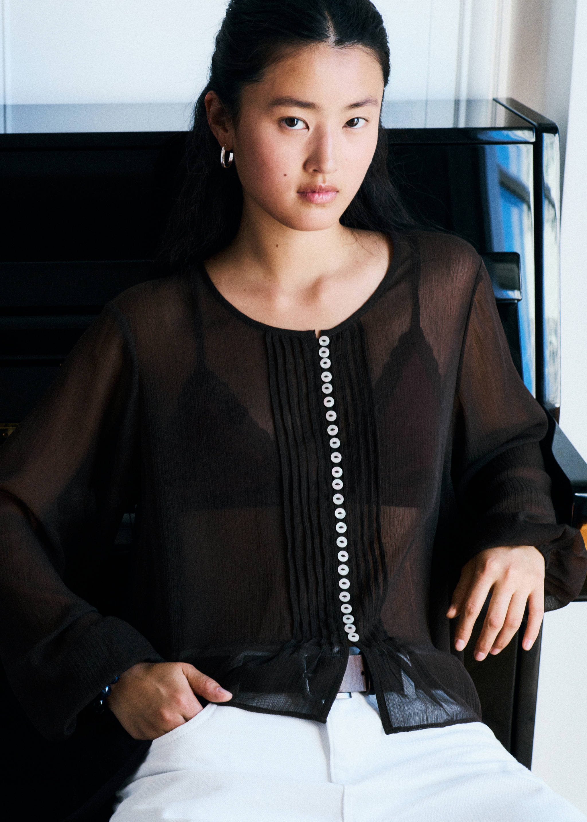 Black sheer long-sleeved shirt with a button-front placket and pleats.