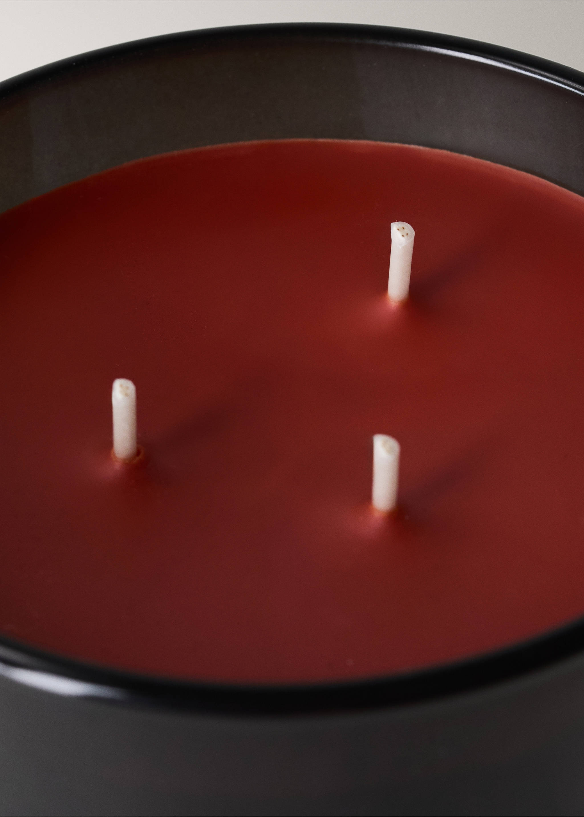 Close-up of a dark red scented candle with three wicks in a dark container., Copper. Ref: 37058278-00.