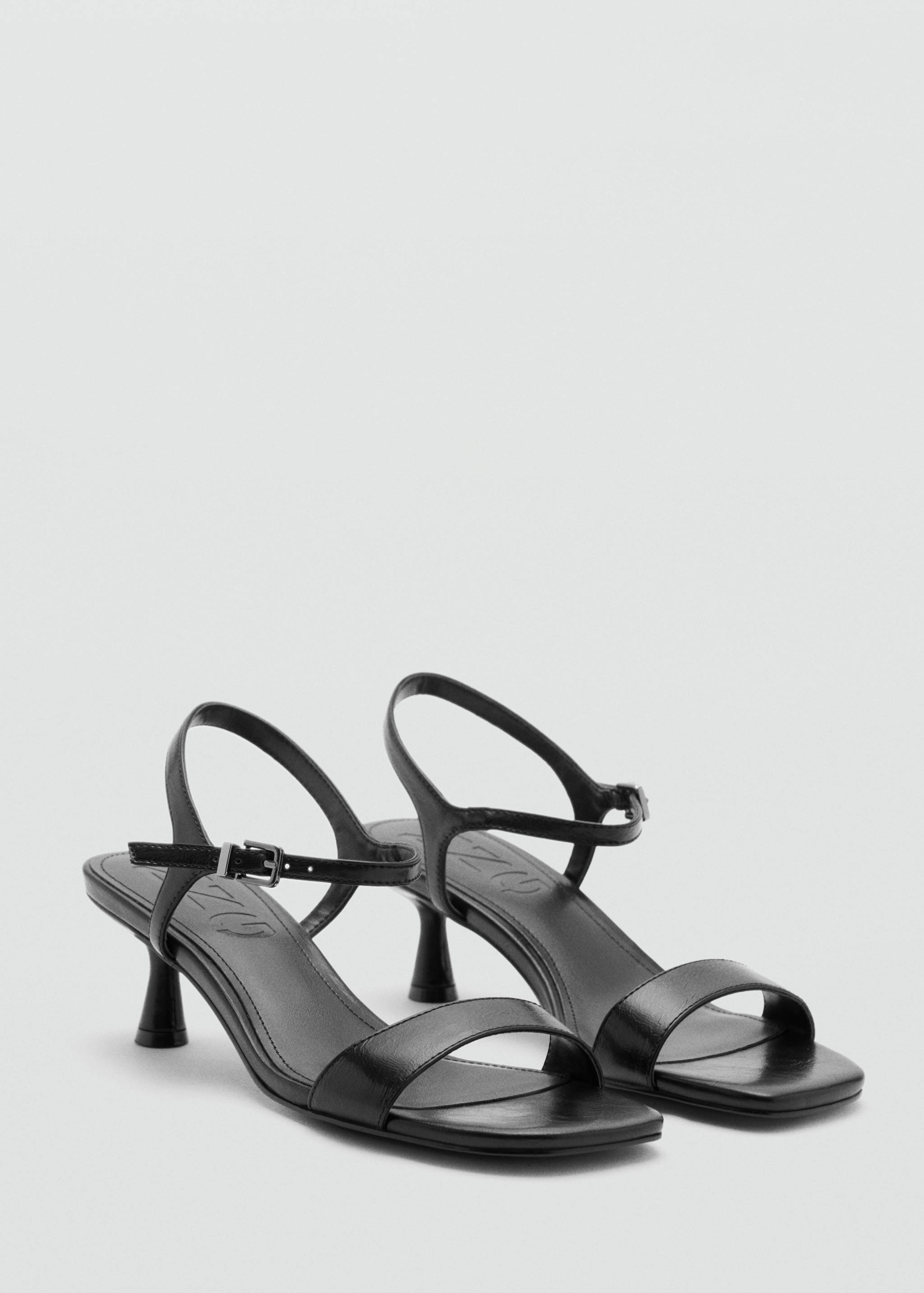 Black heeled sandals with slim toe straps and ankle buckle closures.