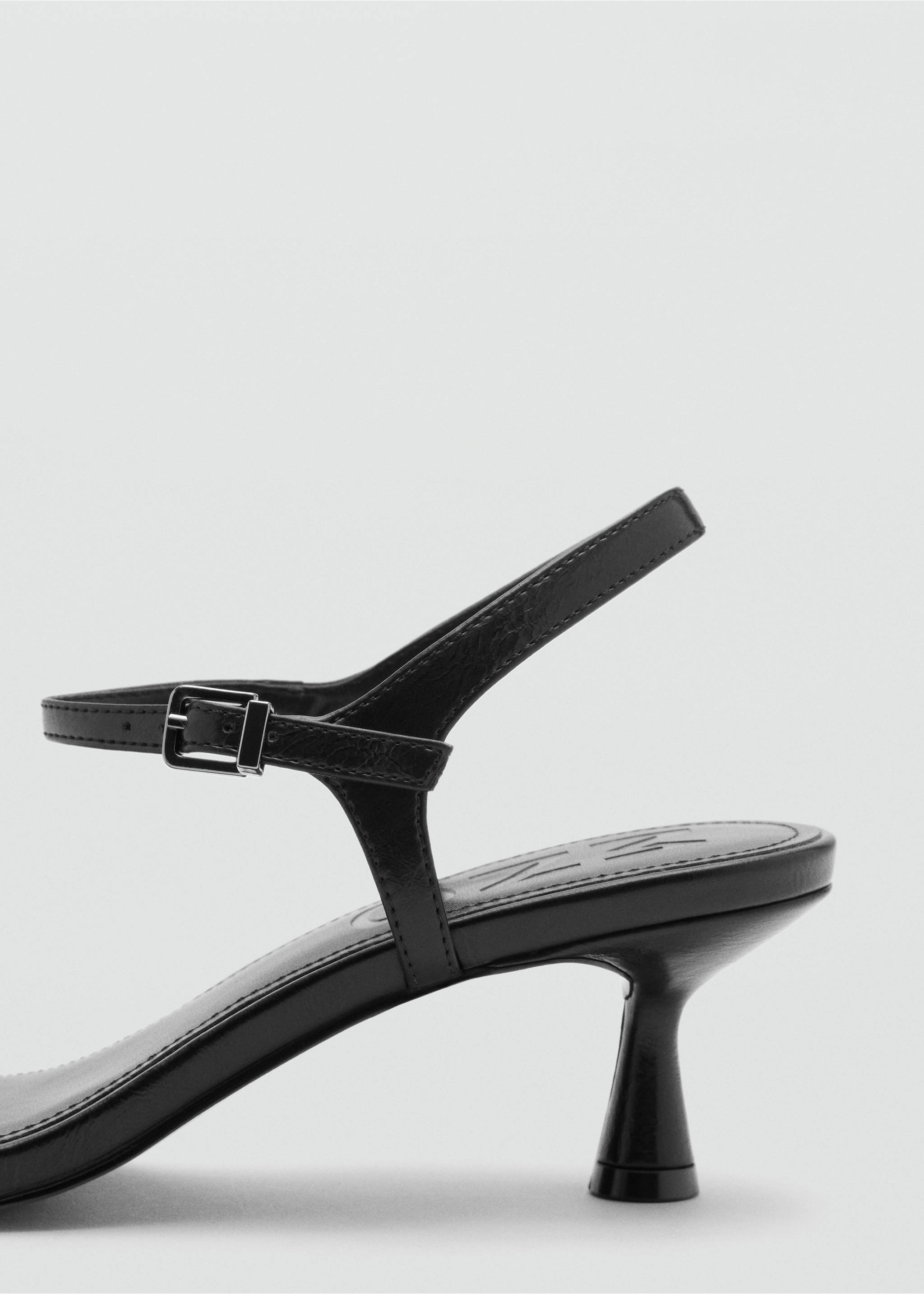 Close-up of the heel and buckled strap detail on a black sandal., Black. Ref: 37058279-00.